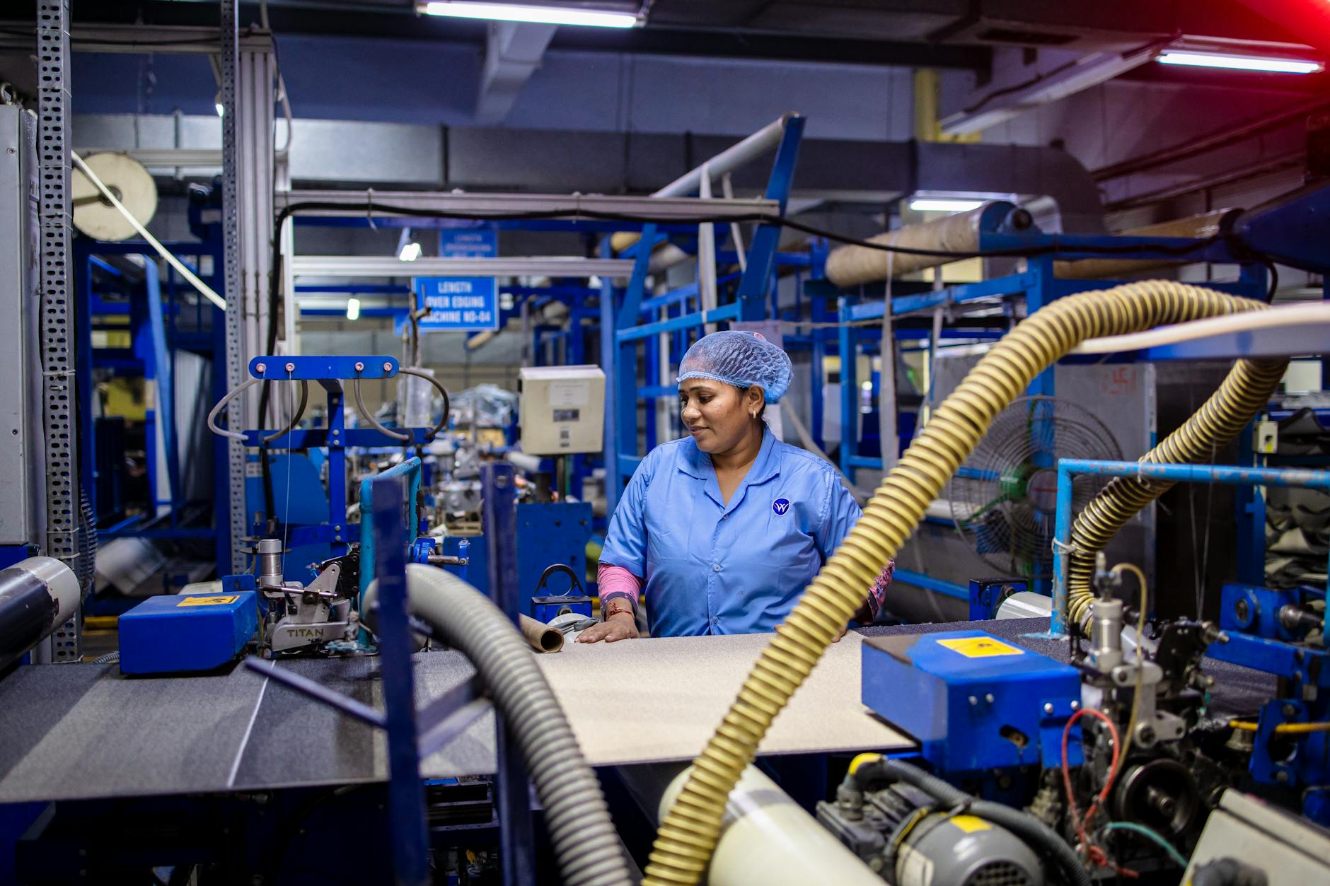 Garment factory worker operating sewing machine in manufacturing facility