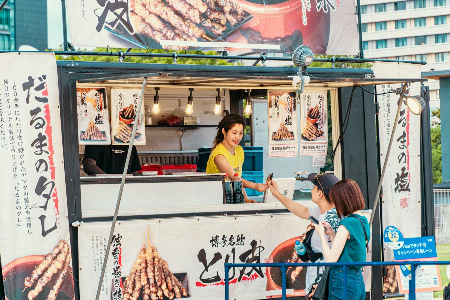 Outdoor festival food vendor setup with people dining at tables under tents