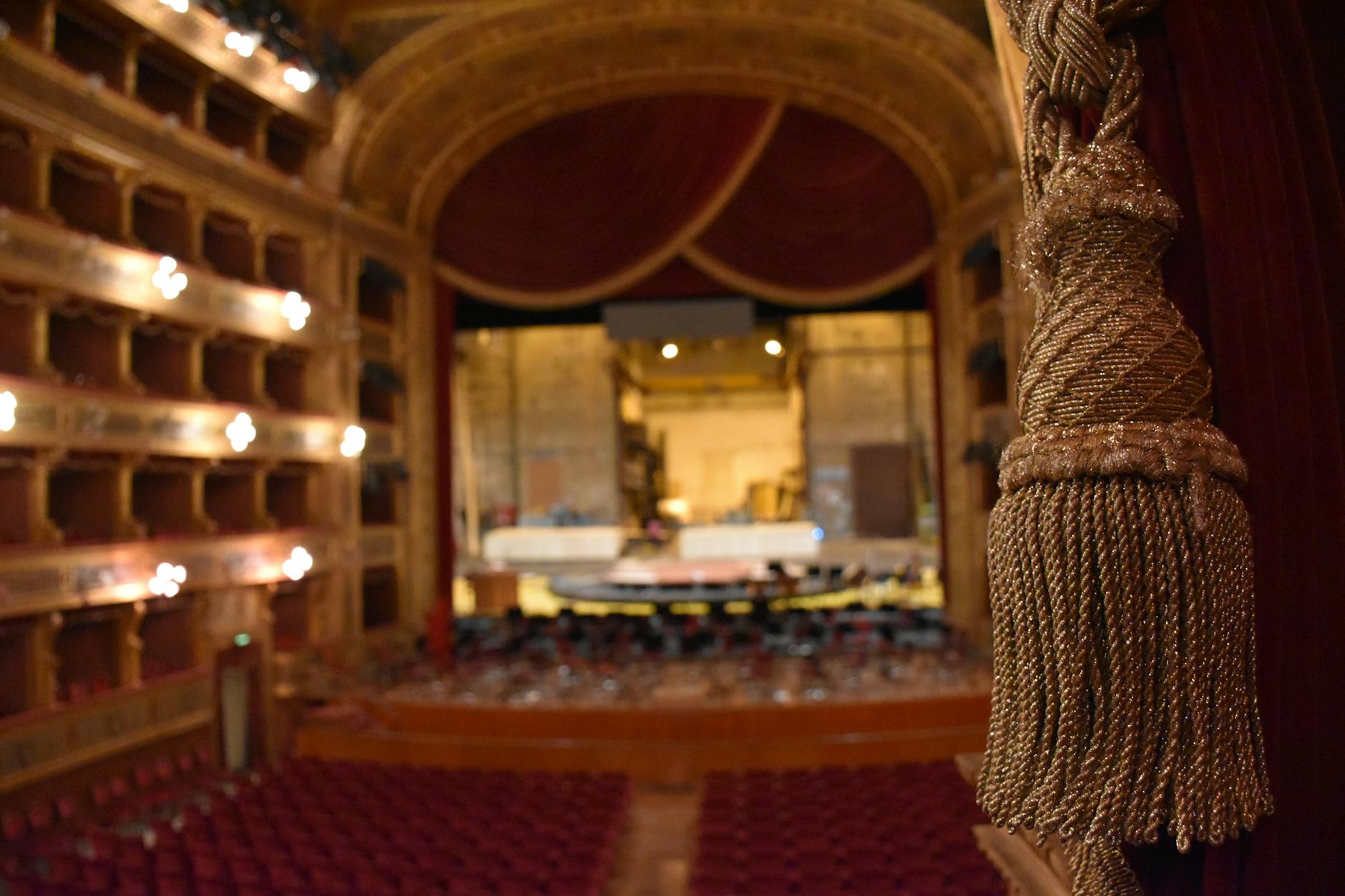 Empty Broadway theater stage with dramatic spotlights and red curtains