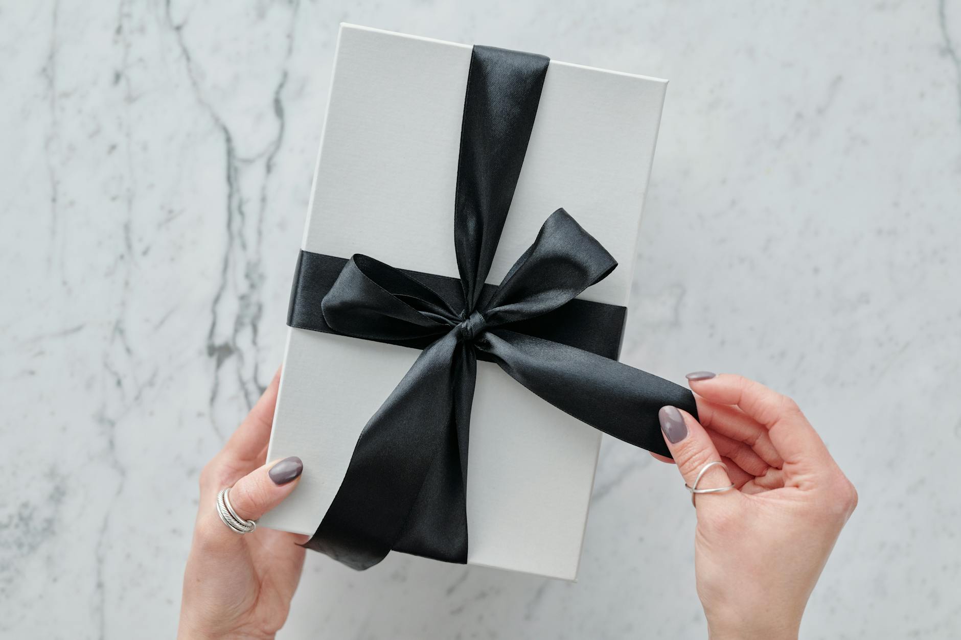 Elegant gift wrapping with ribbons and luxury presentation materials on a marble surface
