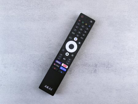 Hand holding TV remote control pointing at screen