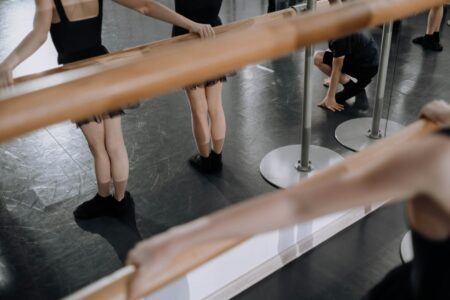 Dancers rehearsing choreography in a professional dance studio with mirrors and barres
