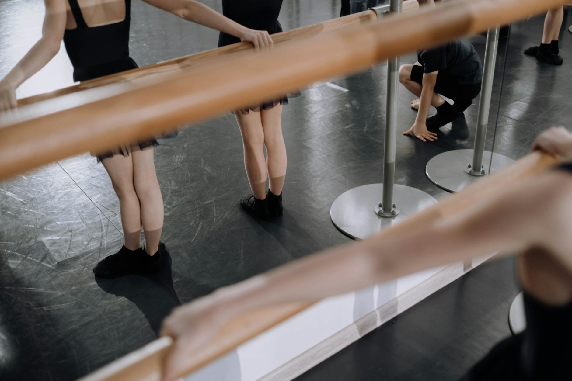 Dancers rehearsing choreography in a professional dance studio with mirrors and barres