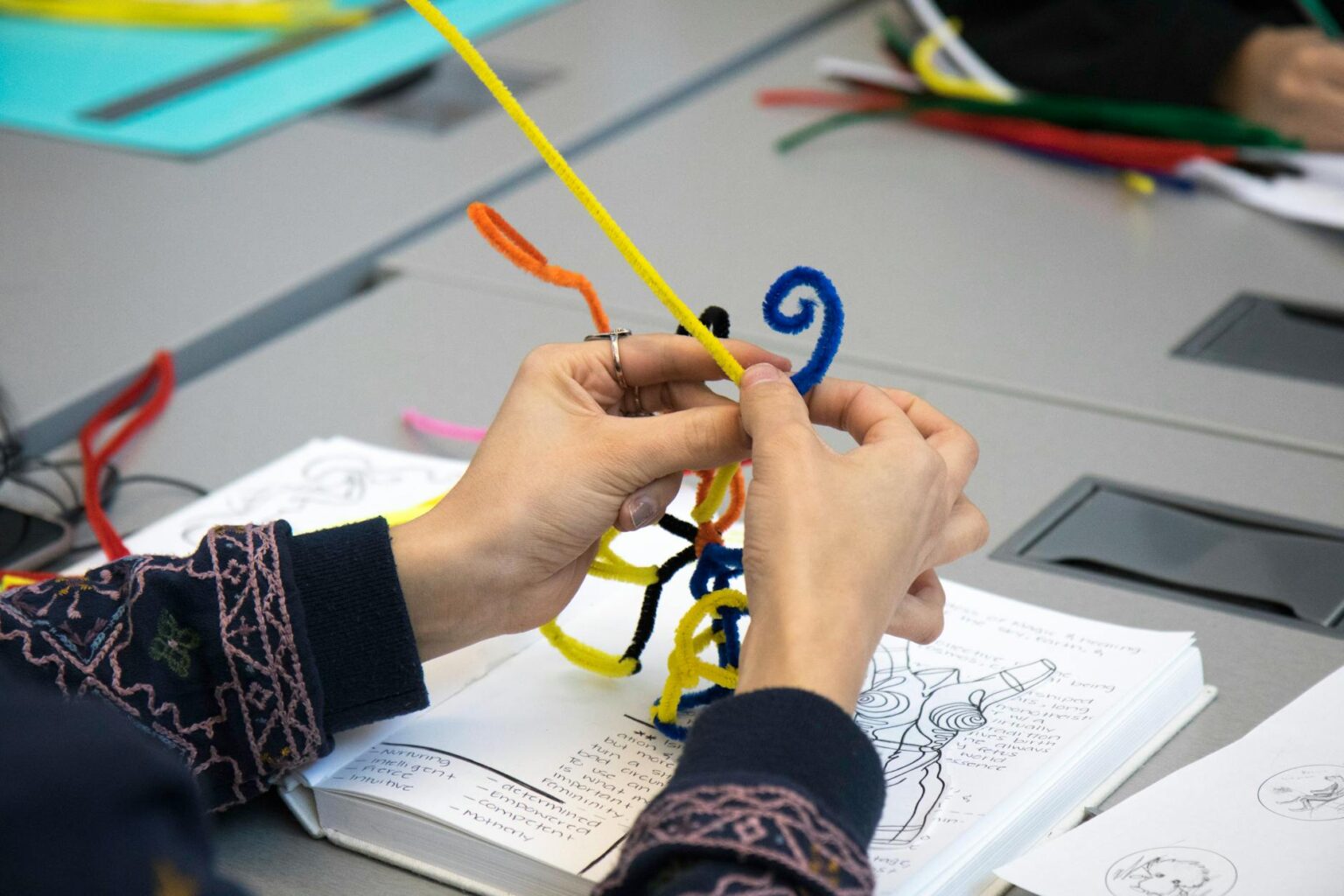 Close-up of hands working on bookbinding, stitching pages together with thread