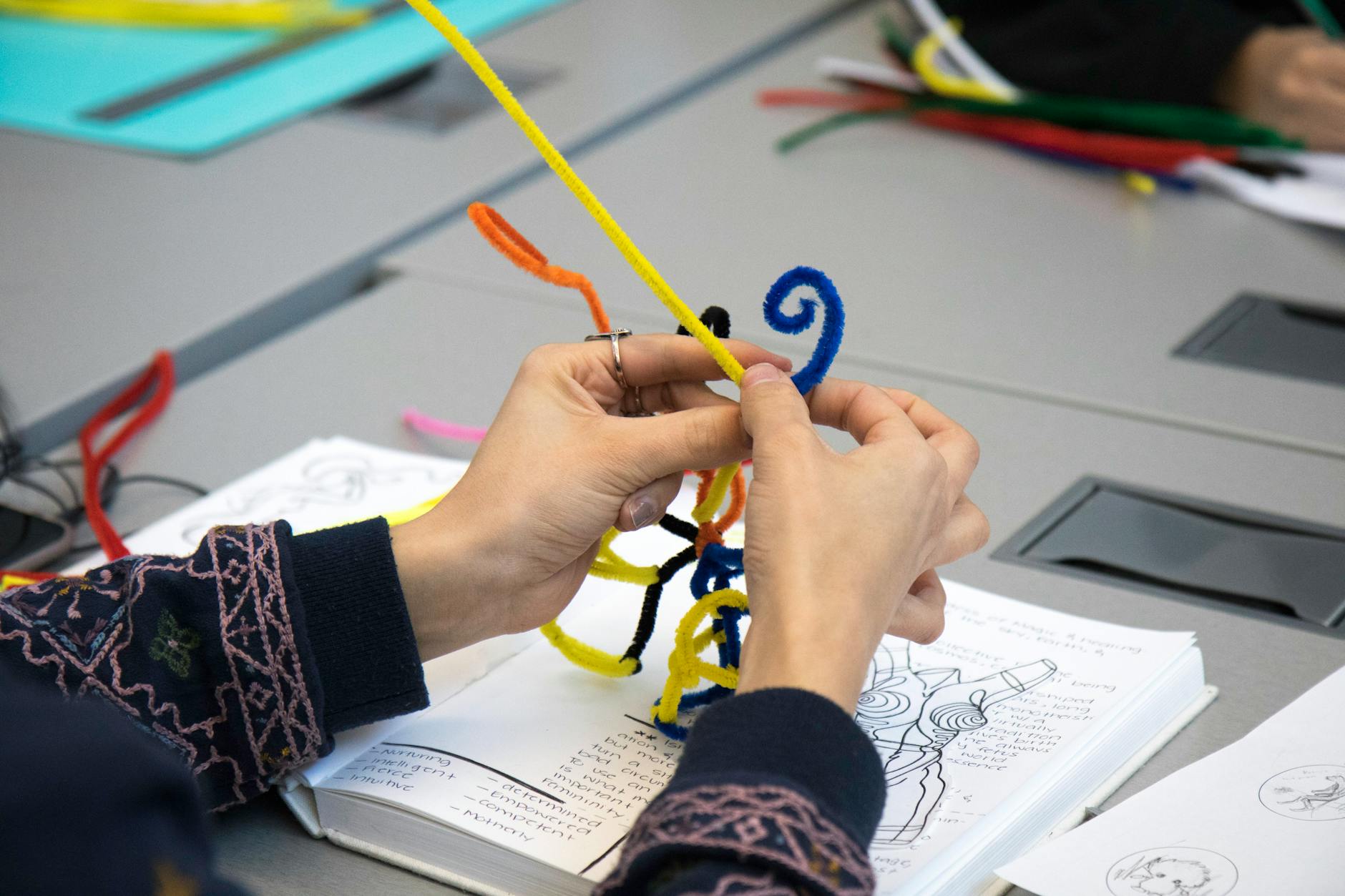 Close-up of hands working on bookbinding, stitching pages together with thread
