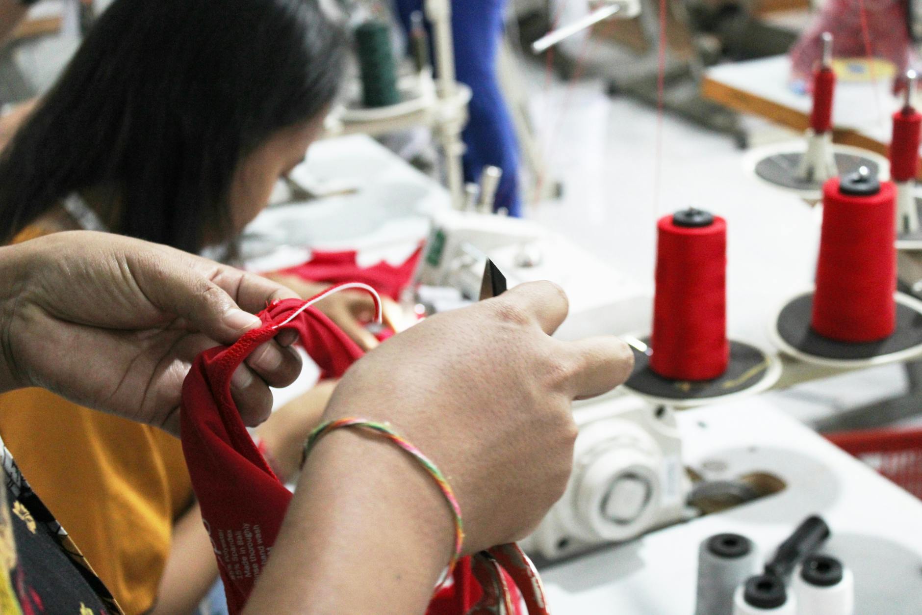 Group of people sitting in a circle working on textile repair projects with sewing supplies