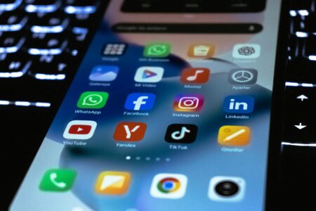 How Social Media Spoilers Are Changing TV Show Release Strategies Person holding smartphone displaying various social media app notifications and feeds