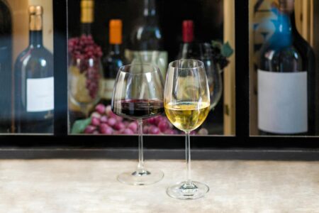 Wine glasses filled with cloudy natural wine on wooden table in trendy wine bar setting