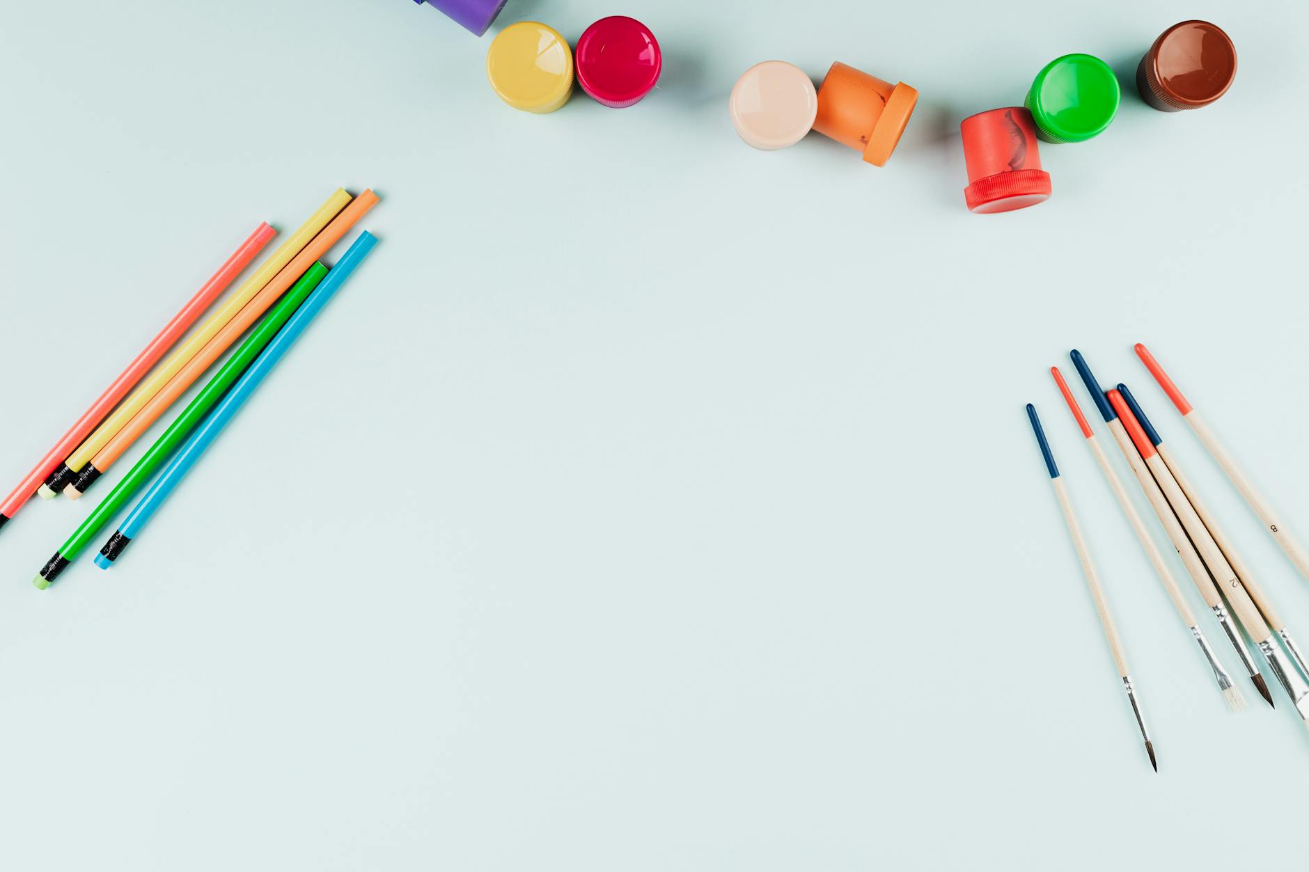 Scattered art supplies including markers, scissors, and colorful paper on desk surface