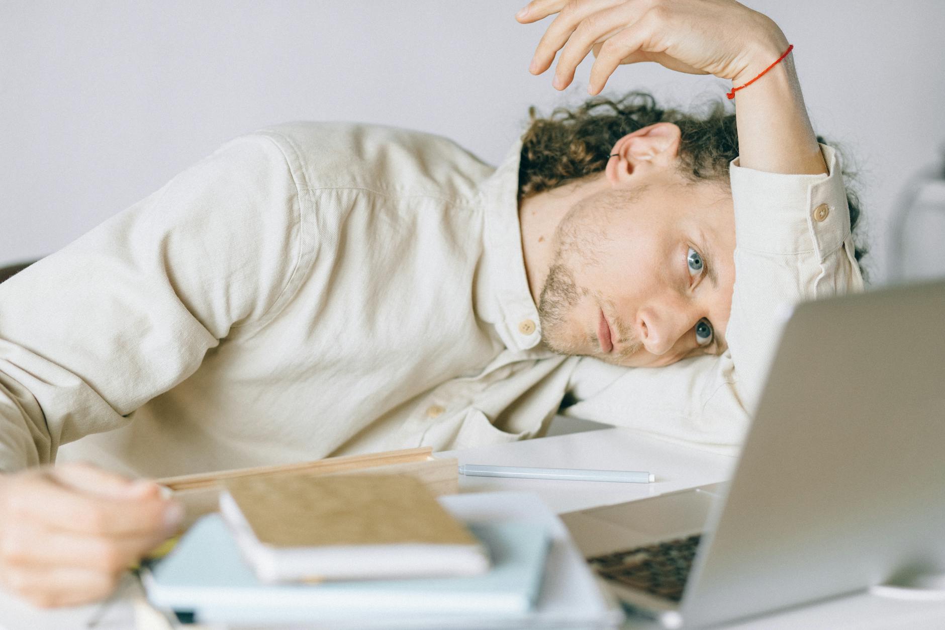 Exhausted office worker holding their head in their hands at a desk covered with papers