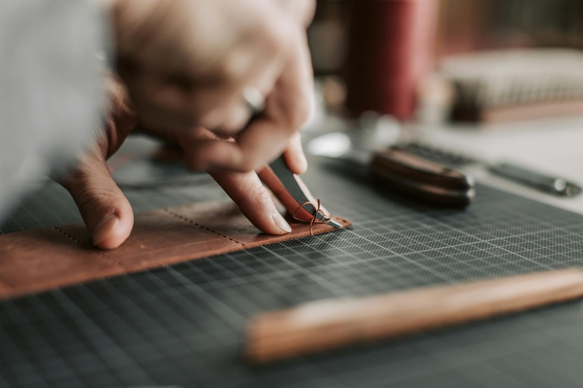 Traditional bookbinding tools and leather materials laid out on wooden workshop table