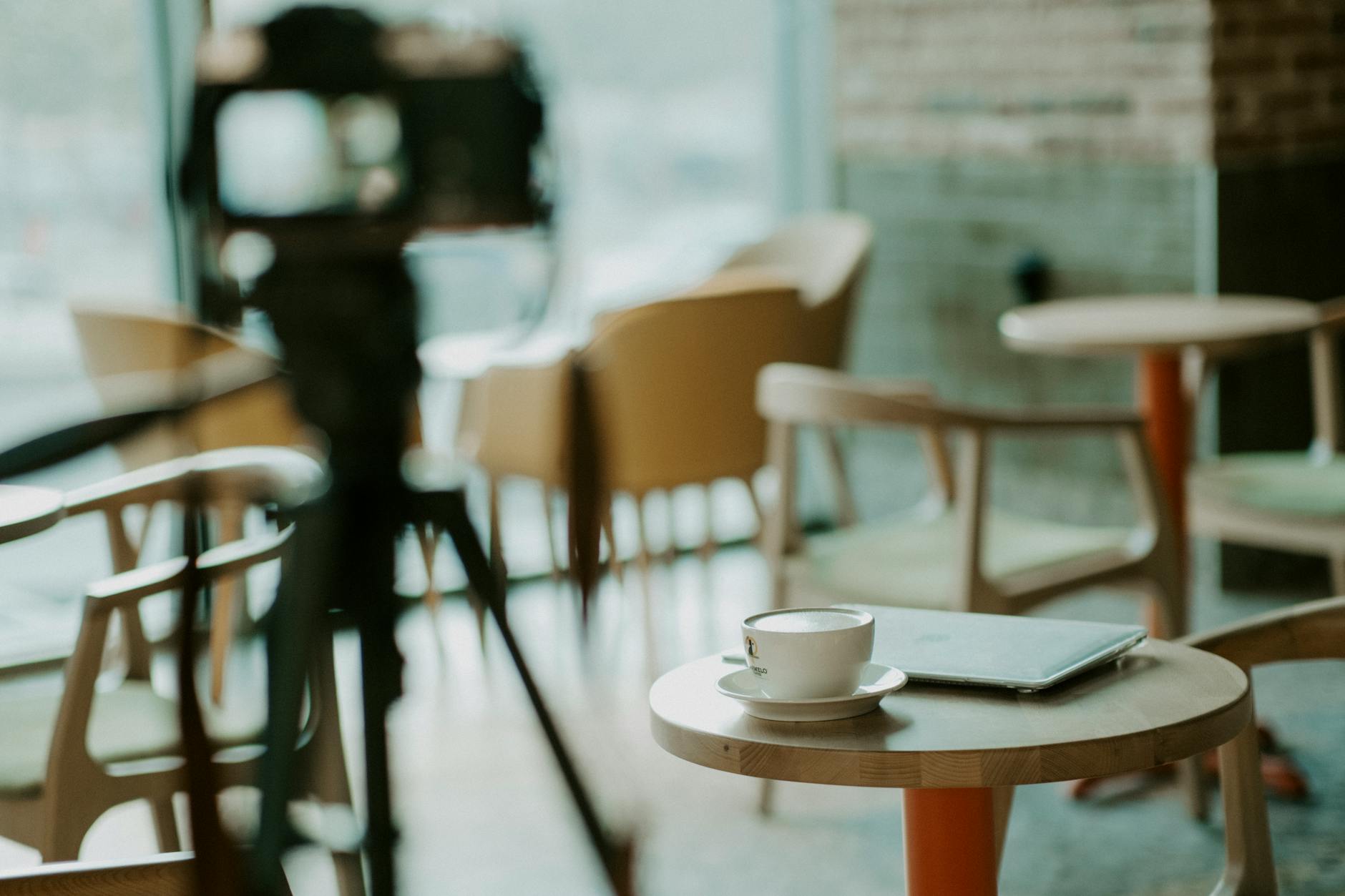 Person working on laptop at coffee shop table with beverage nearby