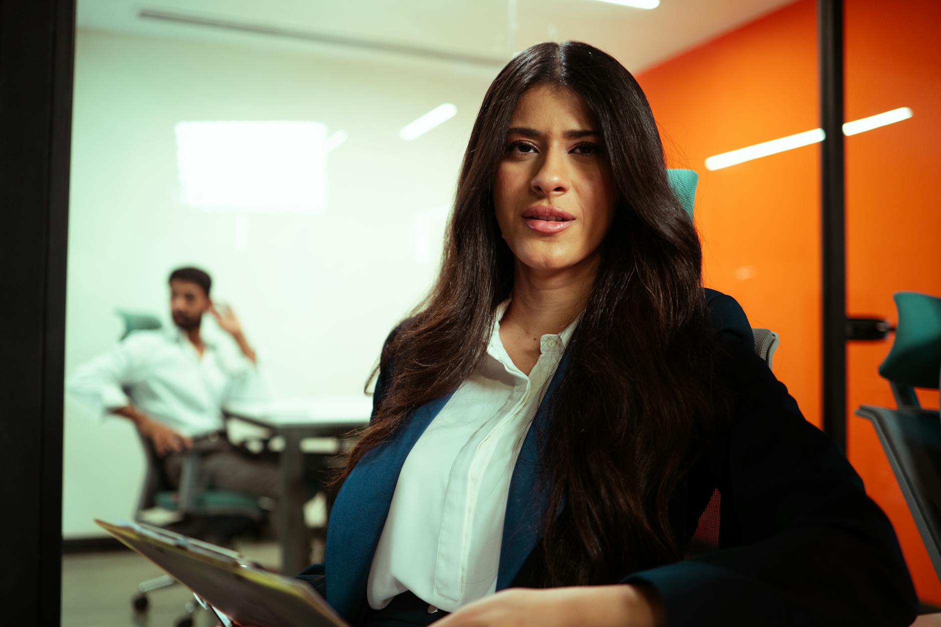 Professional woman in business attire sitting thoughtfully in upscale setting