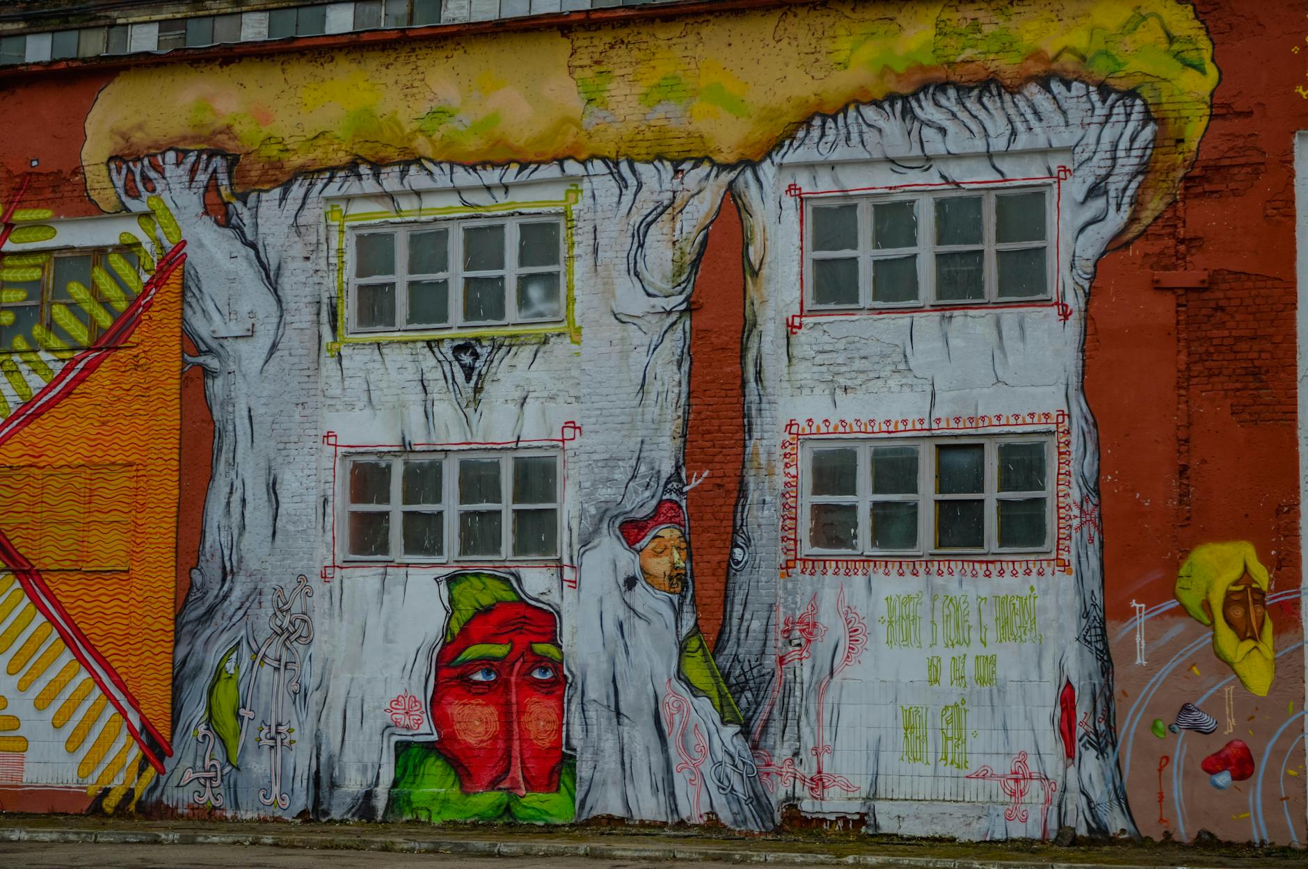 Street artist creating a mural on a wall with spray paint and brushes