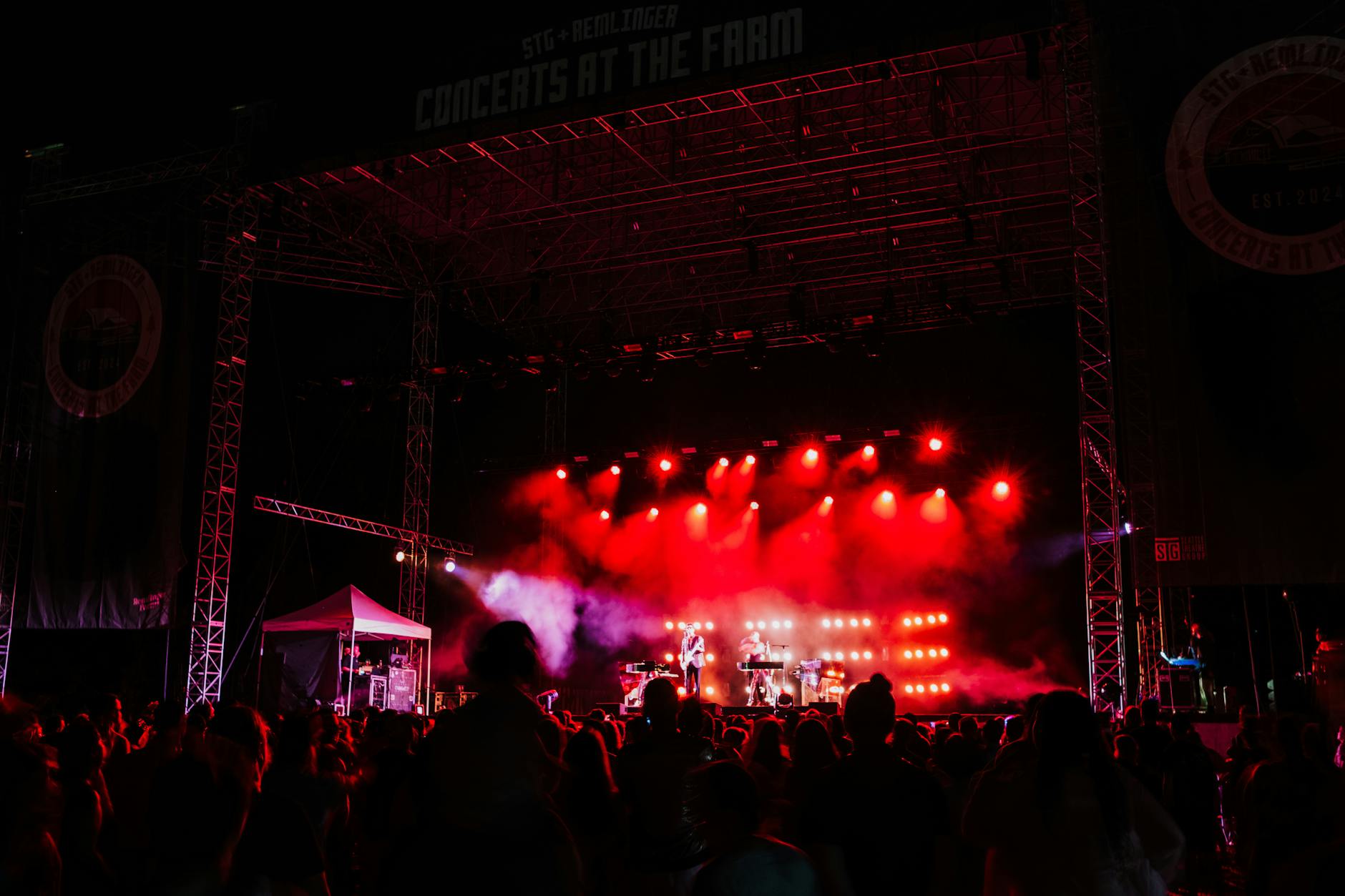 Live music performance on outdoor stage with lighting equipment and audience area