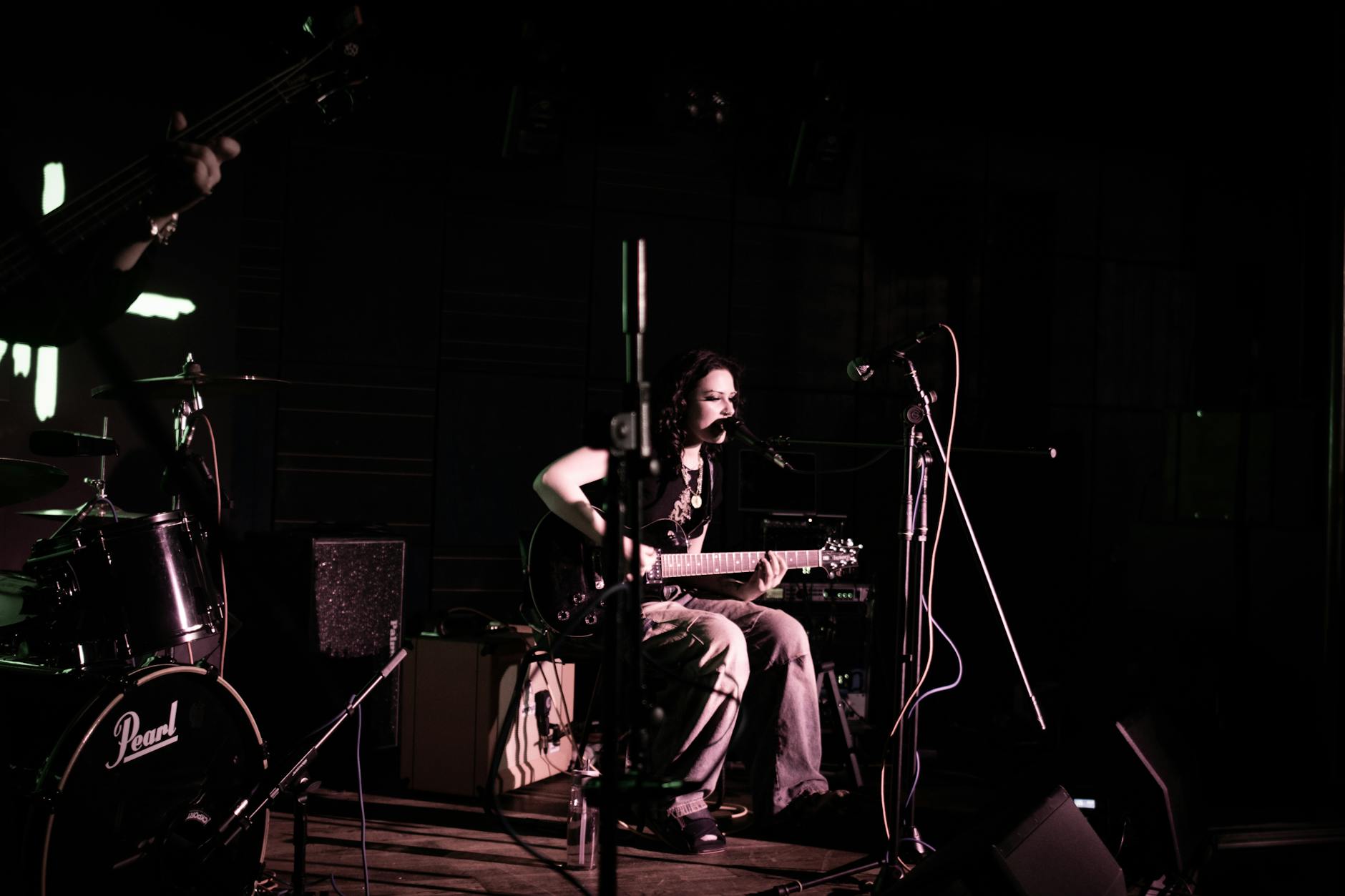 Singer performing on stage with audience in background at intimate venue