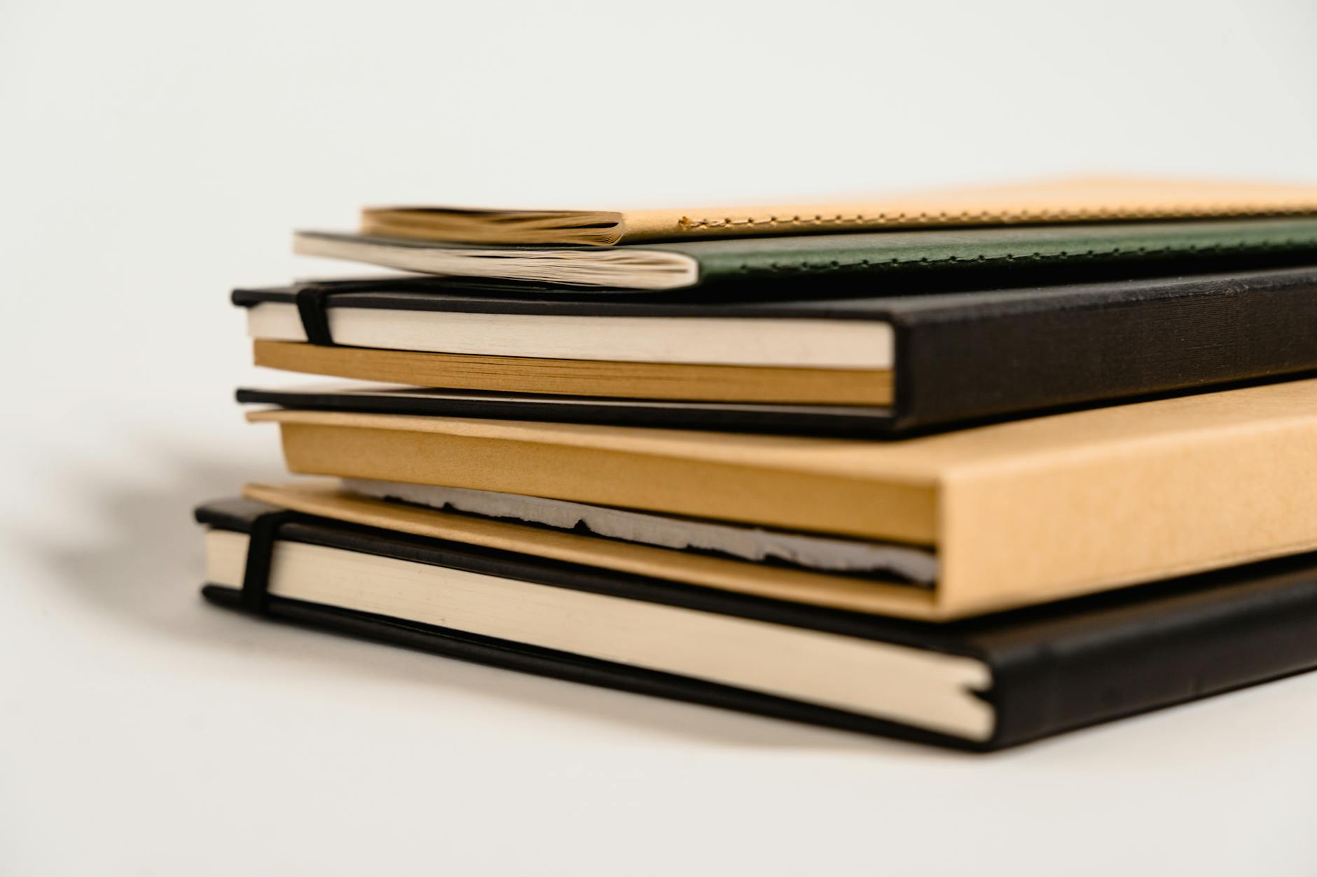 Stack of handbound journals and books with leather covers showing craftsmanship detail