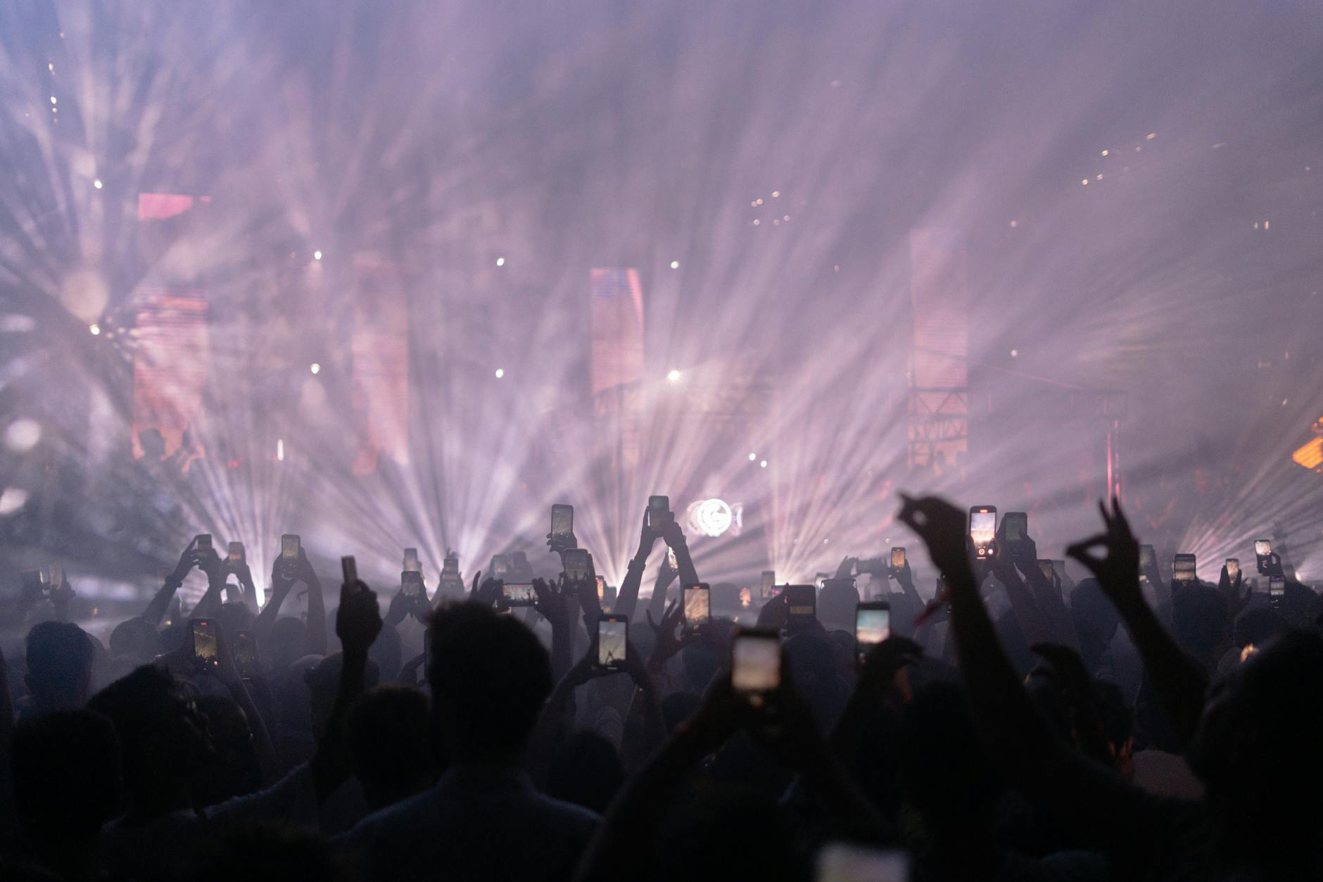 Concert audience holding up smartphones to record live music performance