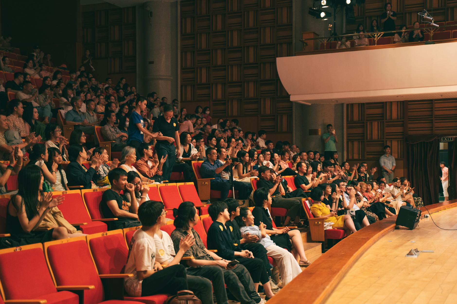 Diverse crowd of young people looking skeptical while watching a performance, representing audience awareness of manufactured authenticity