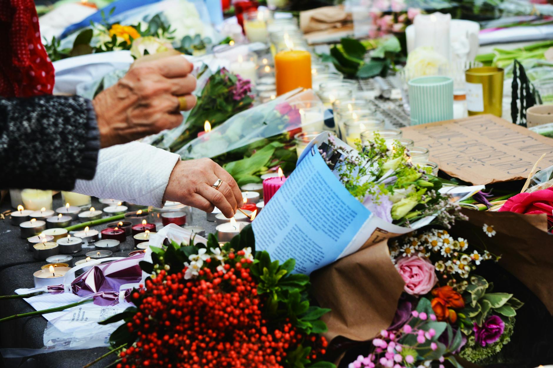 Memorial display with flowers and candles honoring victims, representing the real human cost behind true crime stories