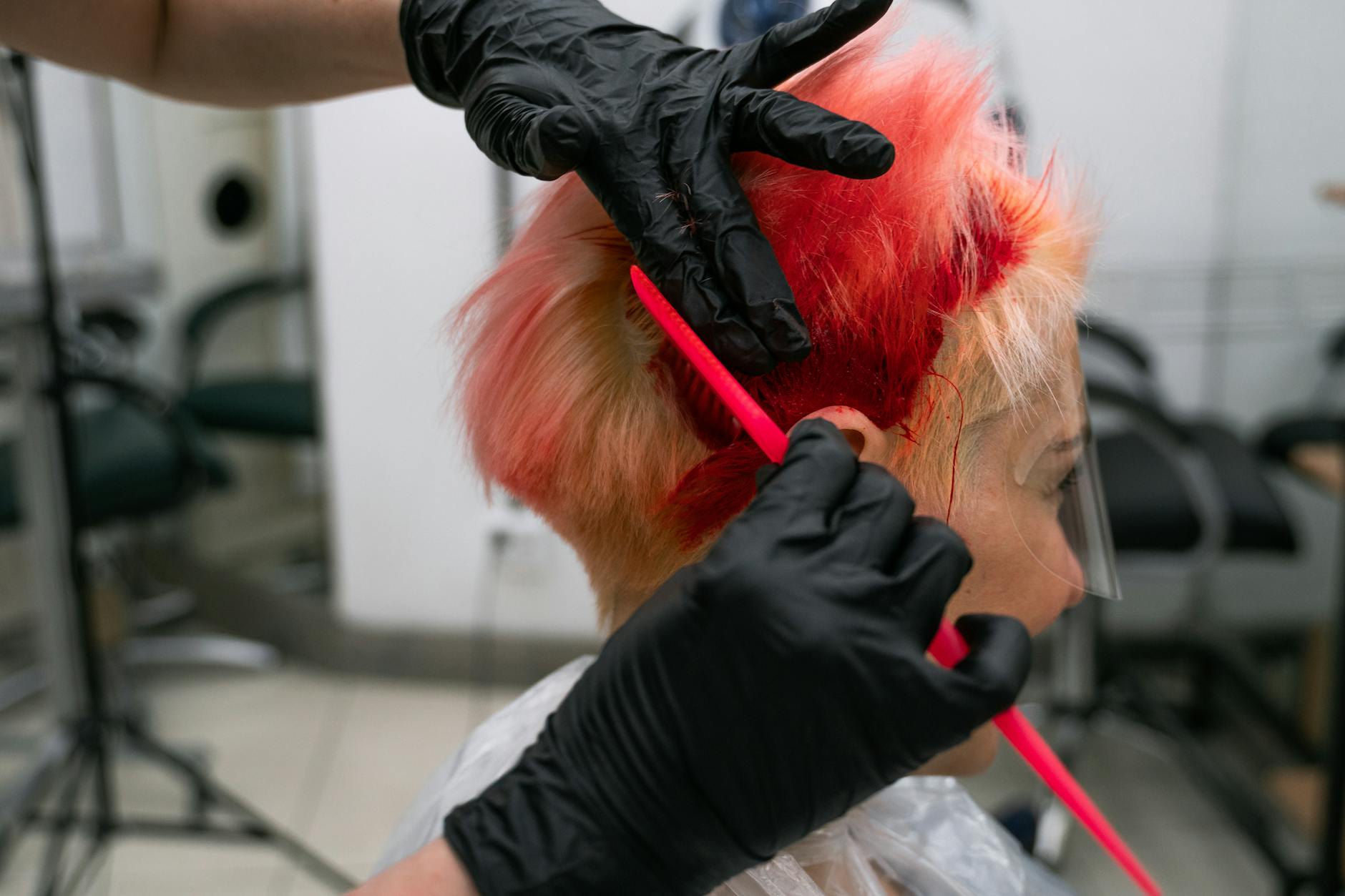Professional hair colorist applying highlights with brush technique