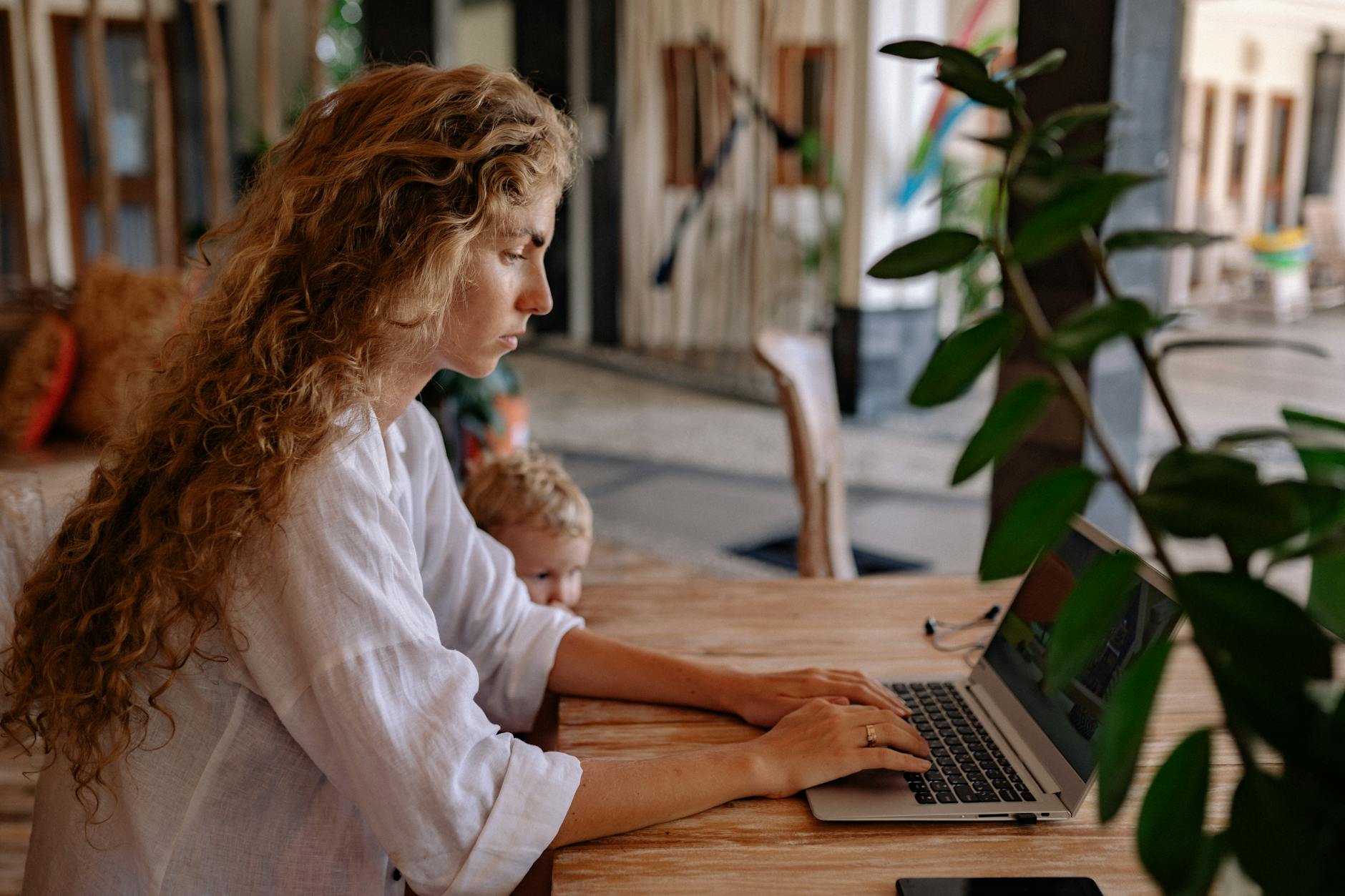 Person working on laptop at home with coffee and plants nearby