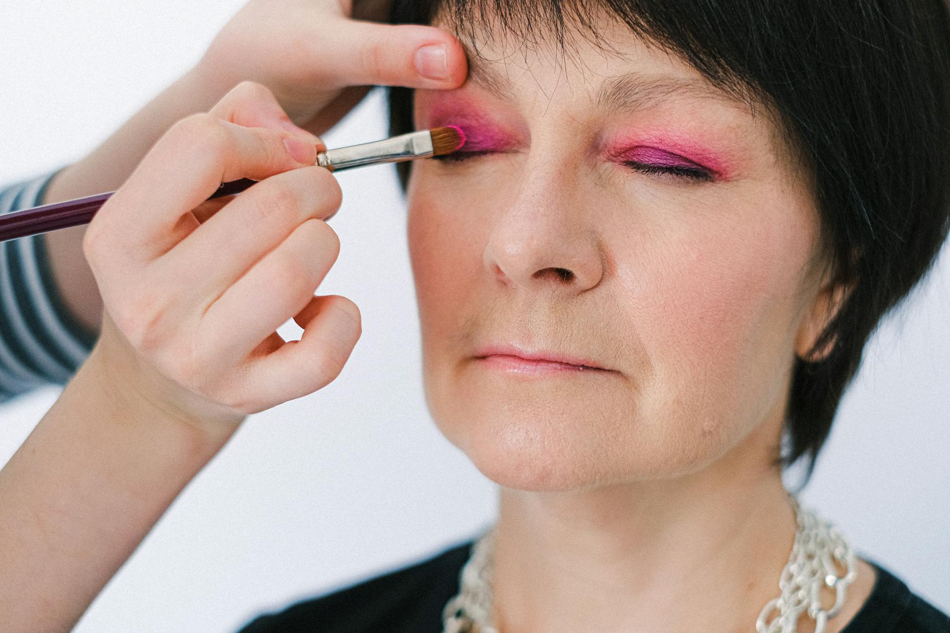 Elegant mature woman applying makeup with professional brush techniques