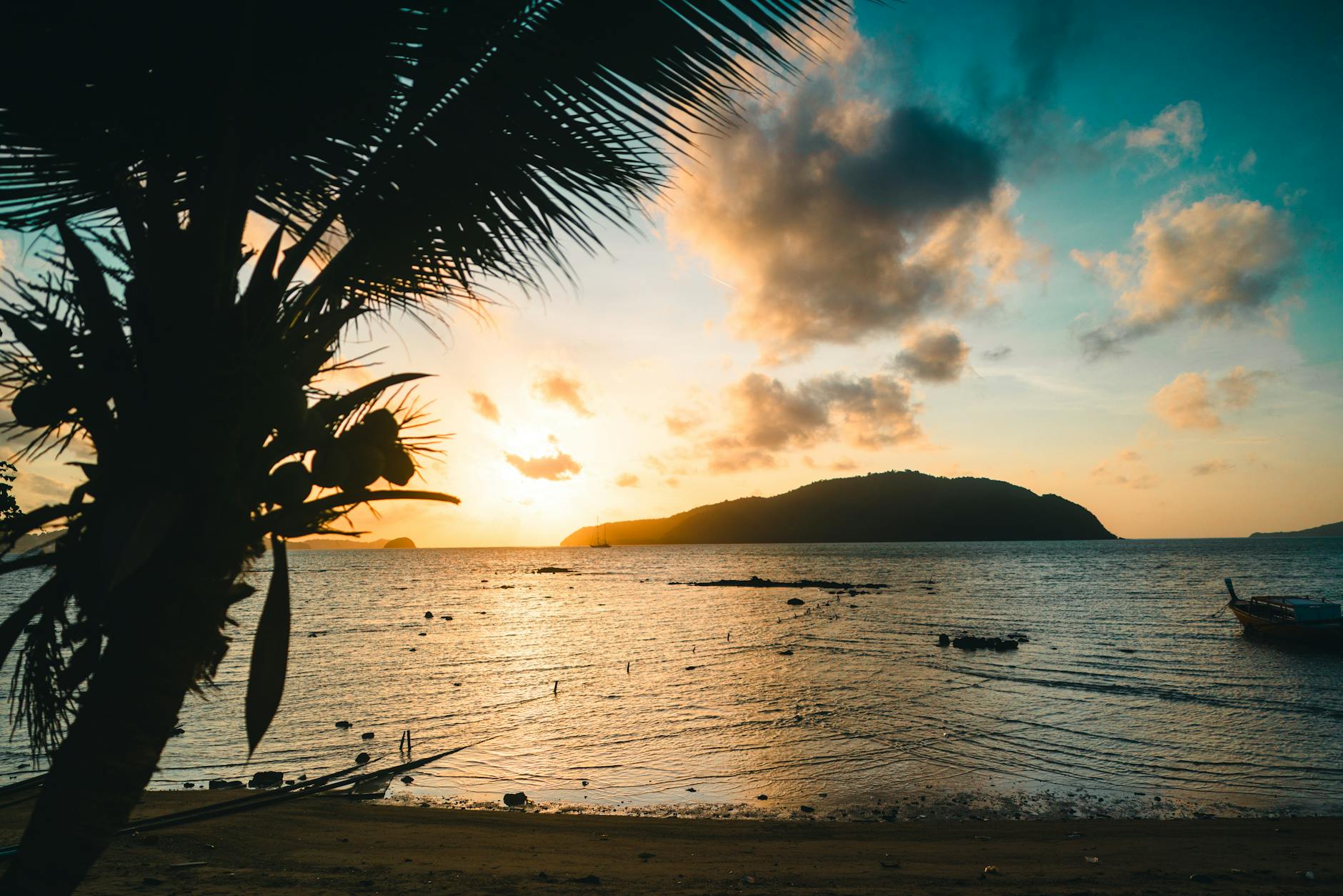 Beautiful sunset over a pristine Thai beach with silhouetted palm trees