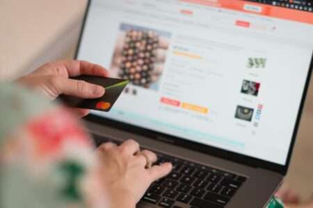 Person browsing products on laptop screen showing various retail websites