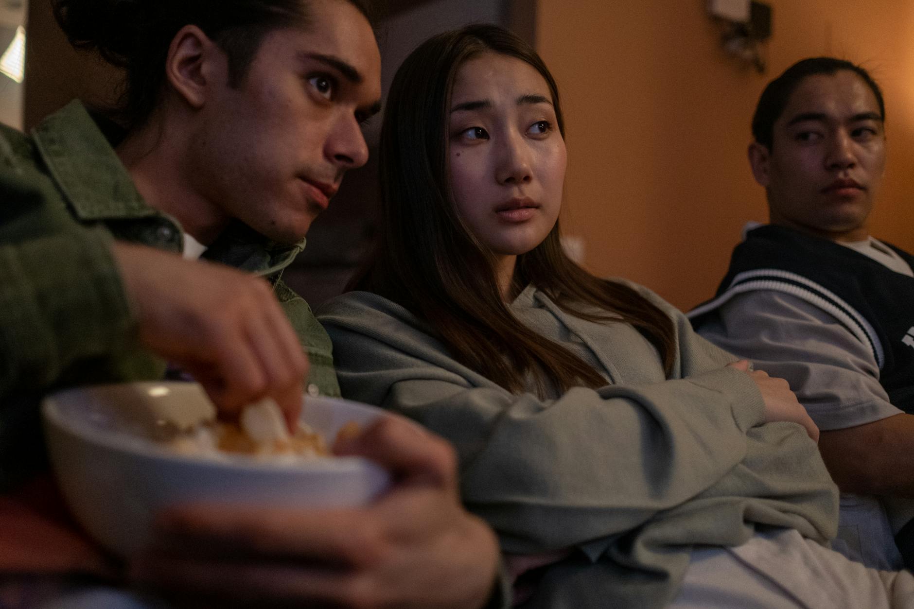 Group of teenagers sitting together watching TV in a living room