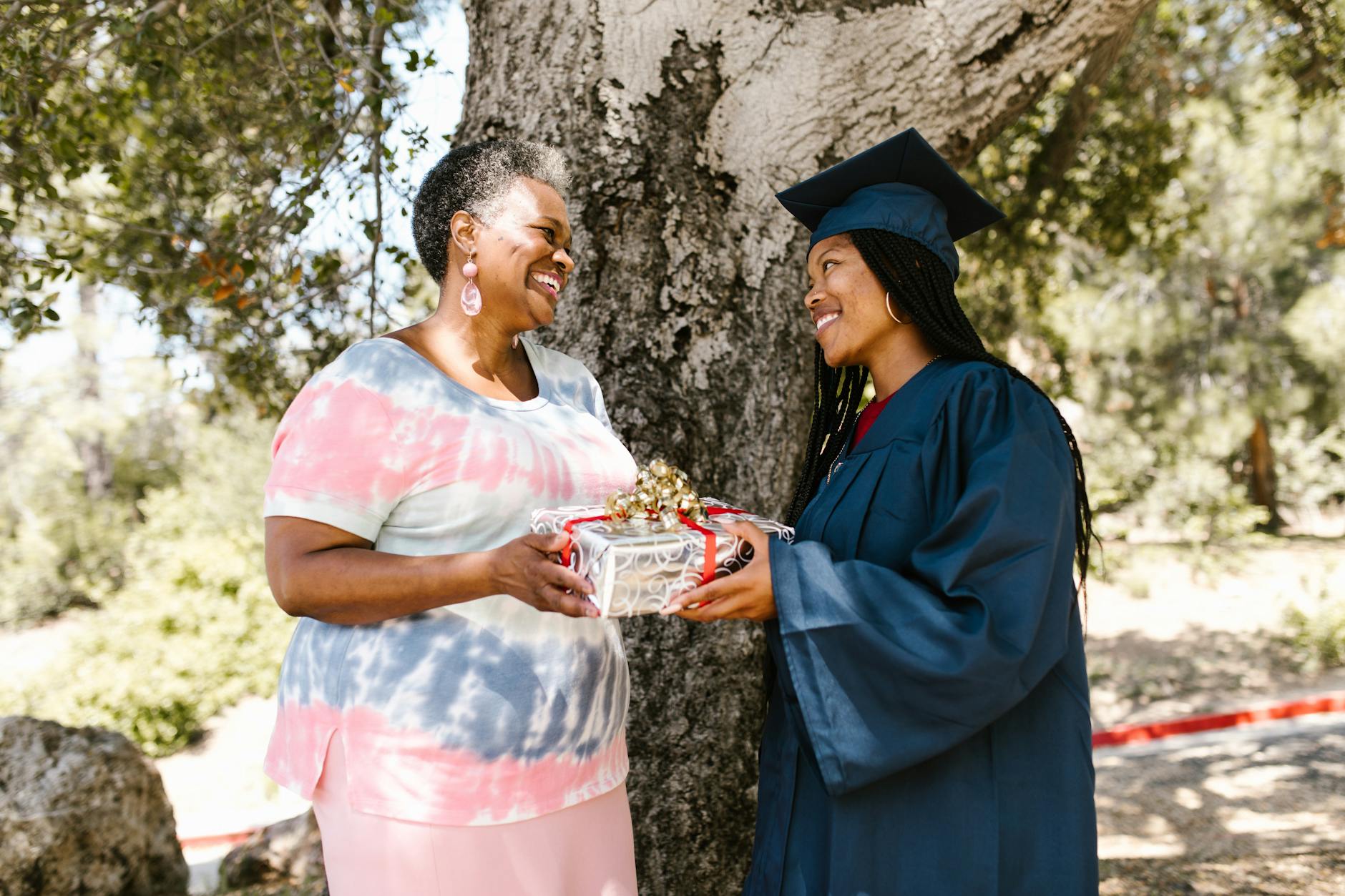 Mother and adult daughter sharing a joyful moment while opening a wrapped gift