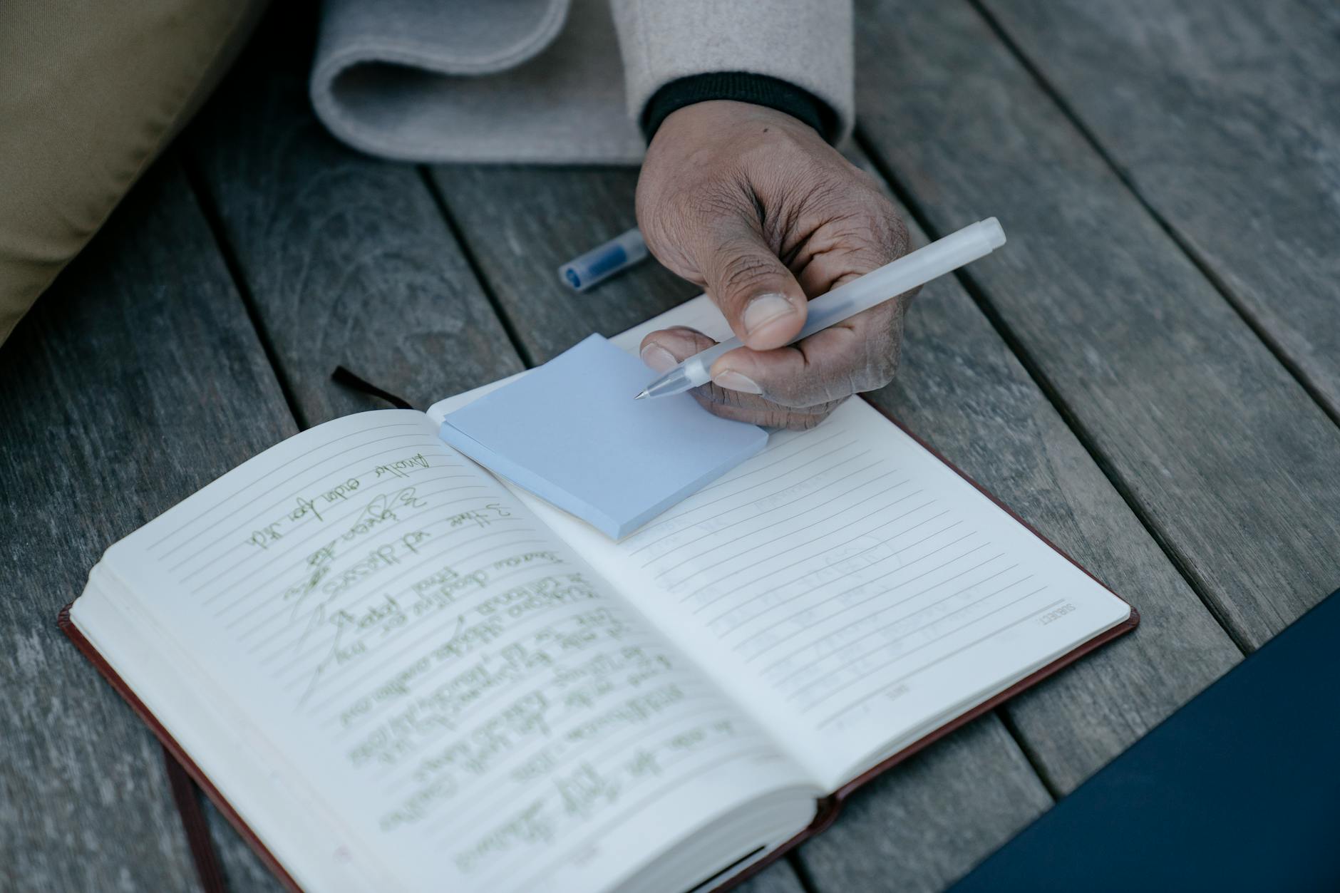 Hand holding pen over open journal with creative writing and brainstorming notes