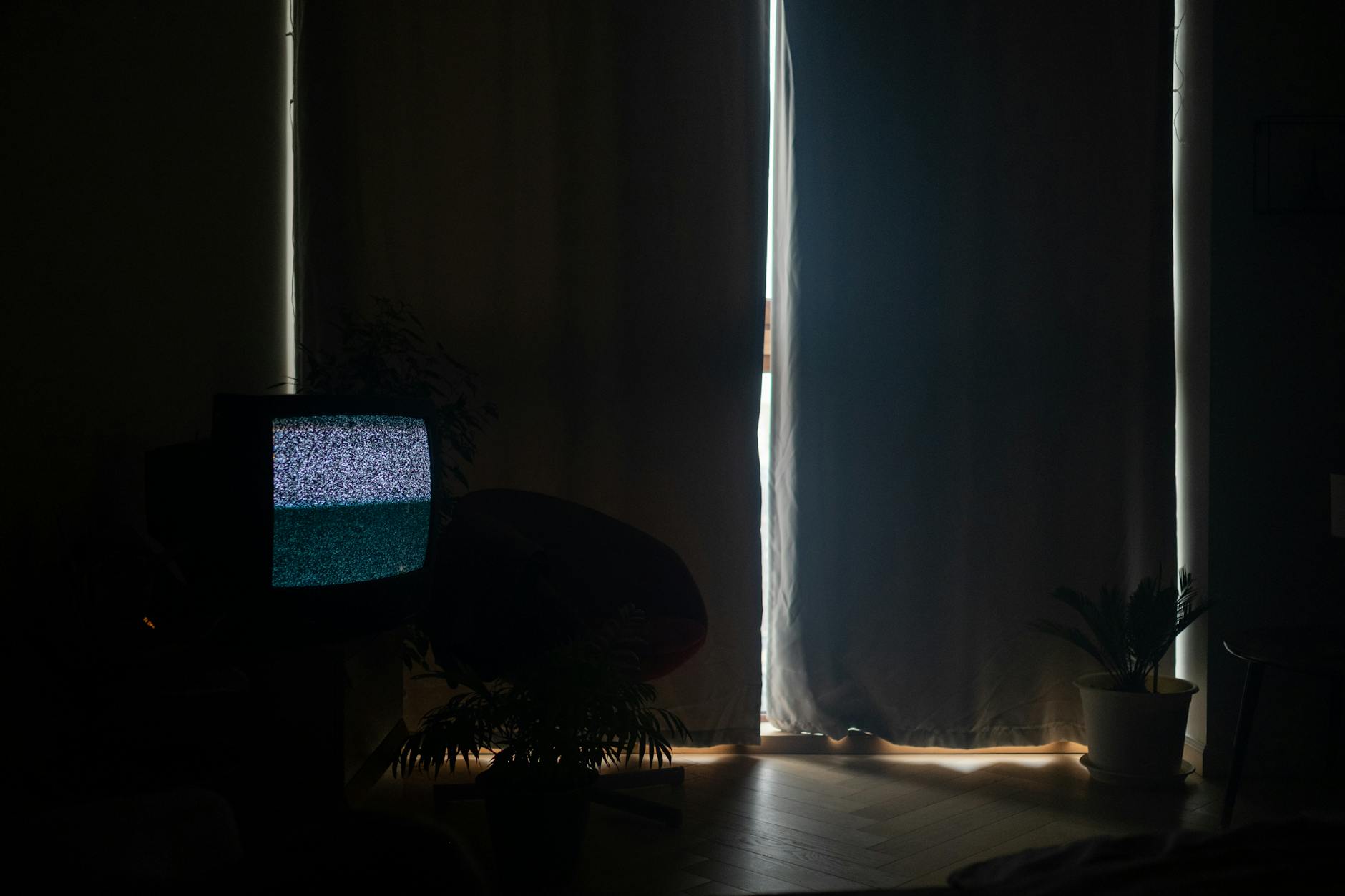 A television glowing in a darkened living room