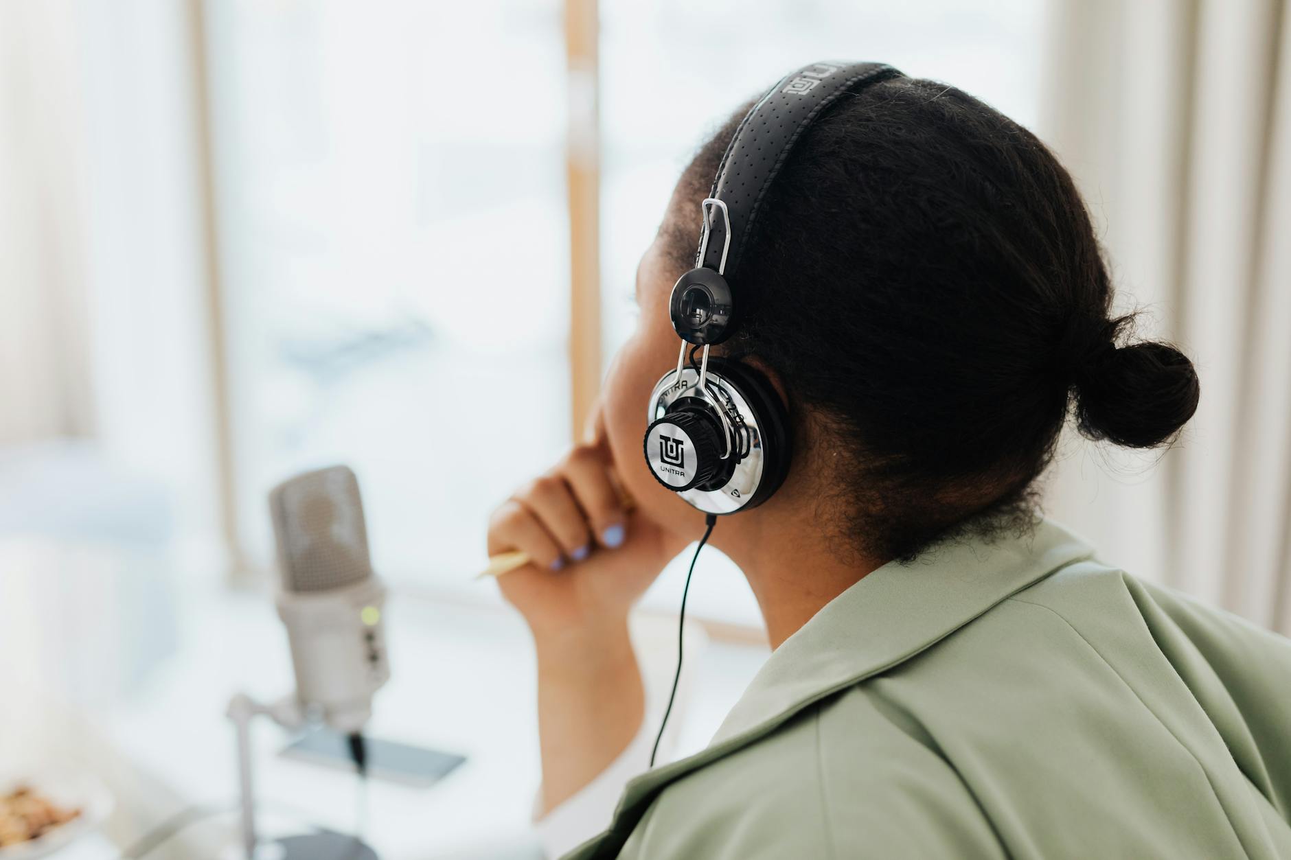 Woman speaking into a podcast microphone in a softly lit studio