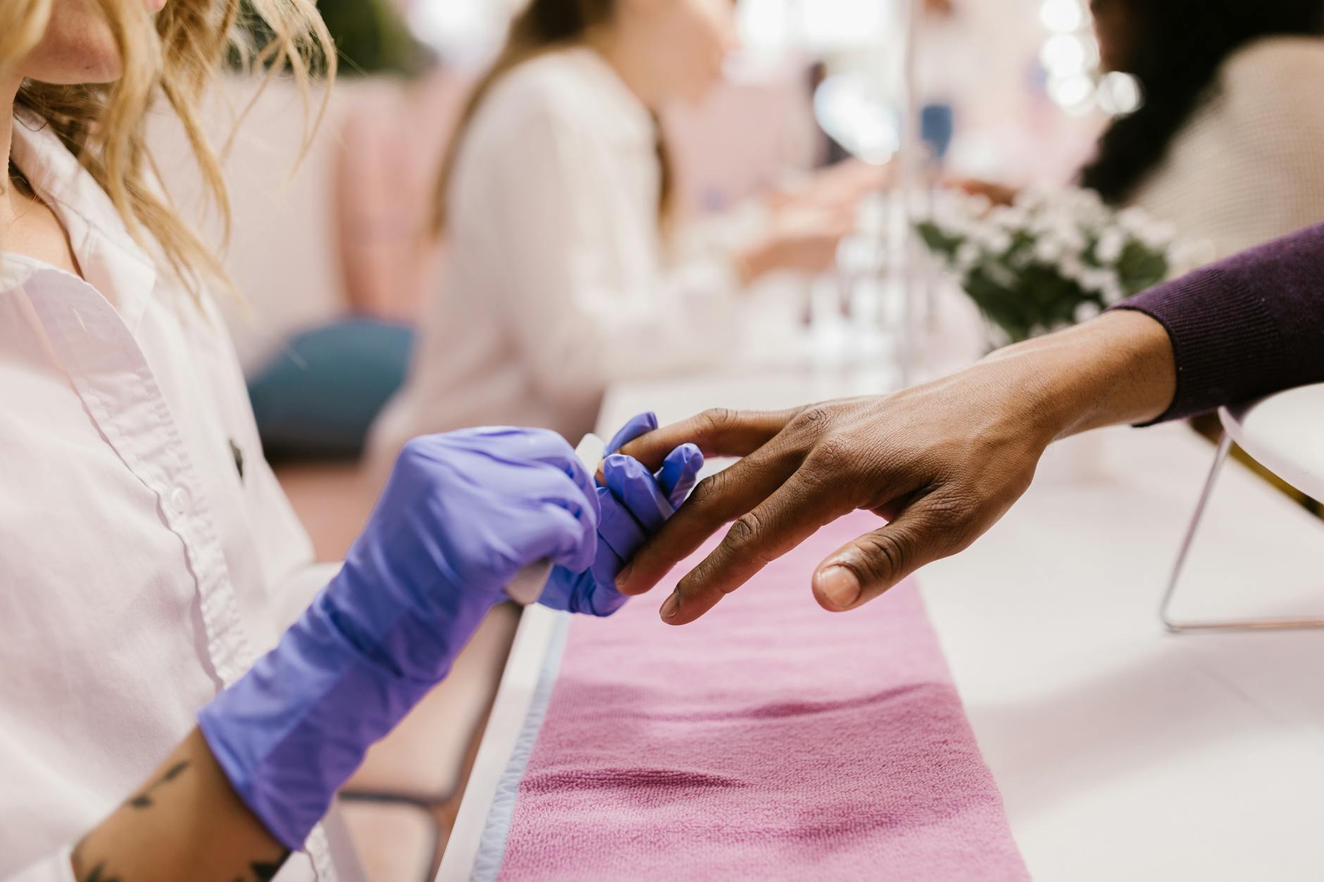 Professional nail technician working on client's manicure in salon setting