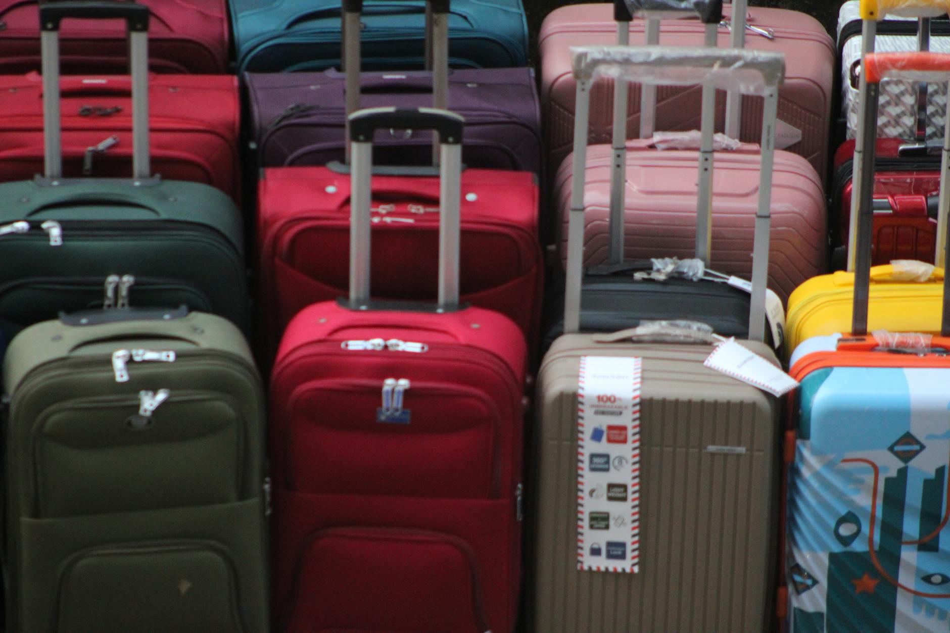 Open suitcase packed for summer travel on a light wood floor