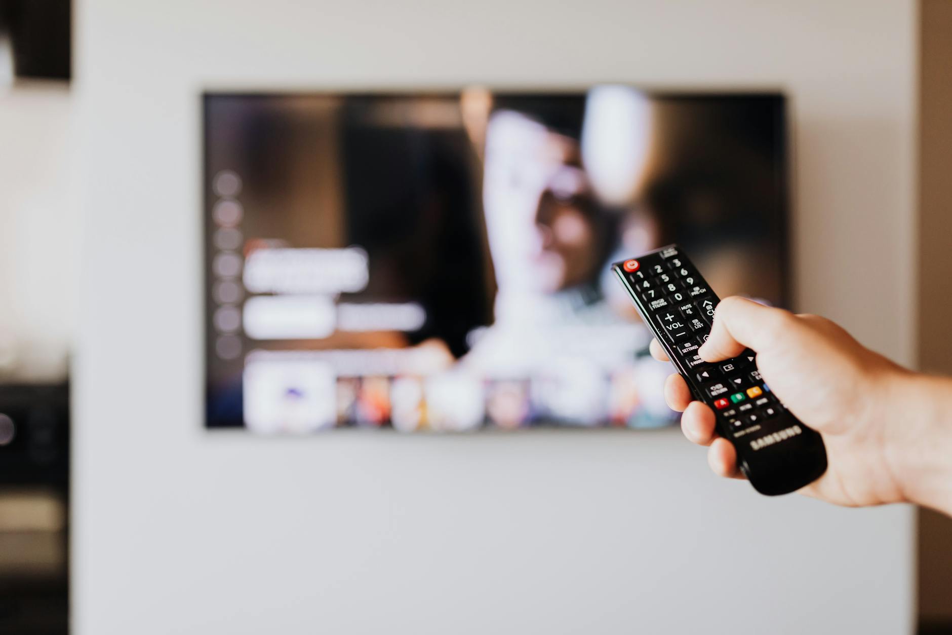 Person holding a remote control in front of a television streaming service