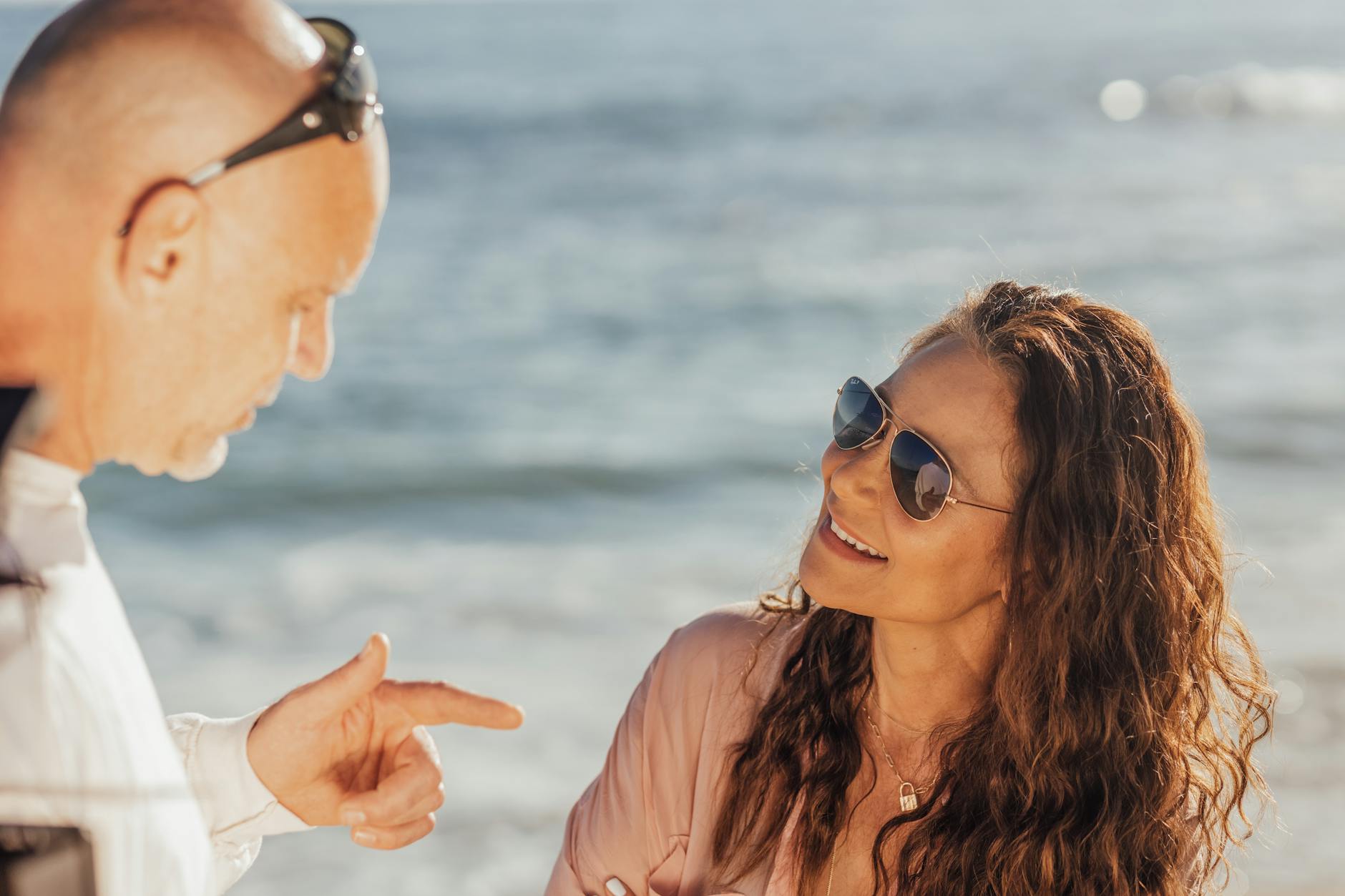 Two people sitting outdoors in conversation, faces partially turned toward each other