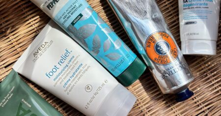Various foot cream containers and tubes arranged on white background