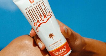 Person applying sunscreen lotion to their arm outdoors