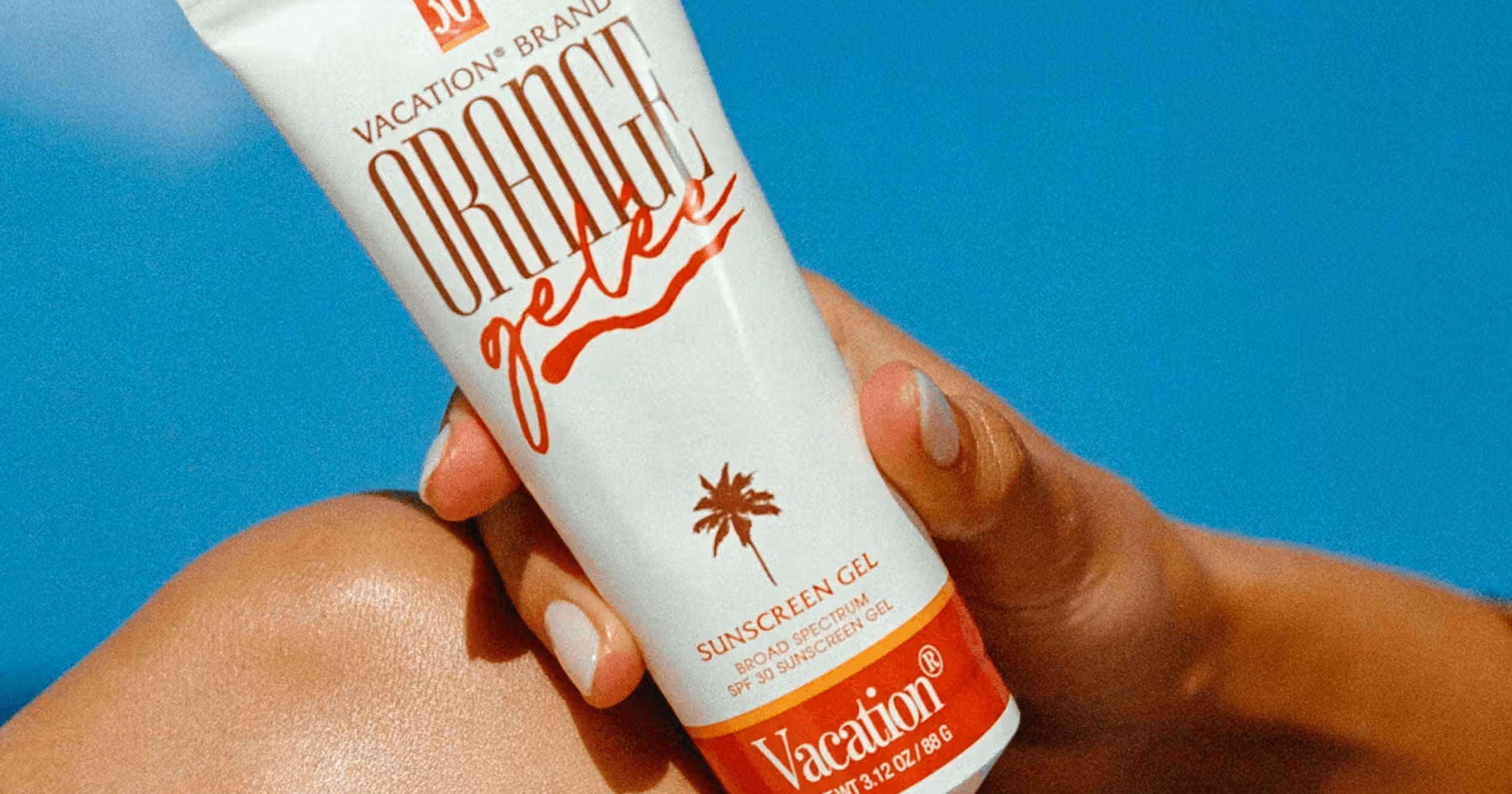 Person applying sunscreen lotion to their arm outdoors