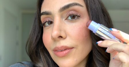 Kosas Impressionist Multistick Does Lips, Cheeks, and Lids for $34 A cream blush stick resting on a marble surface next to a small mirror