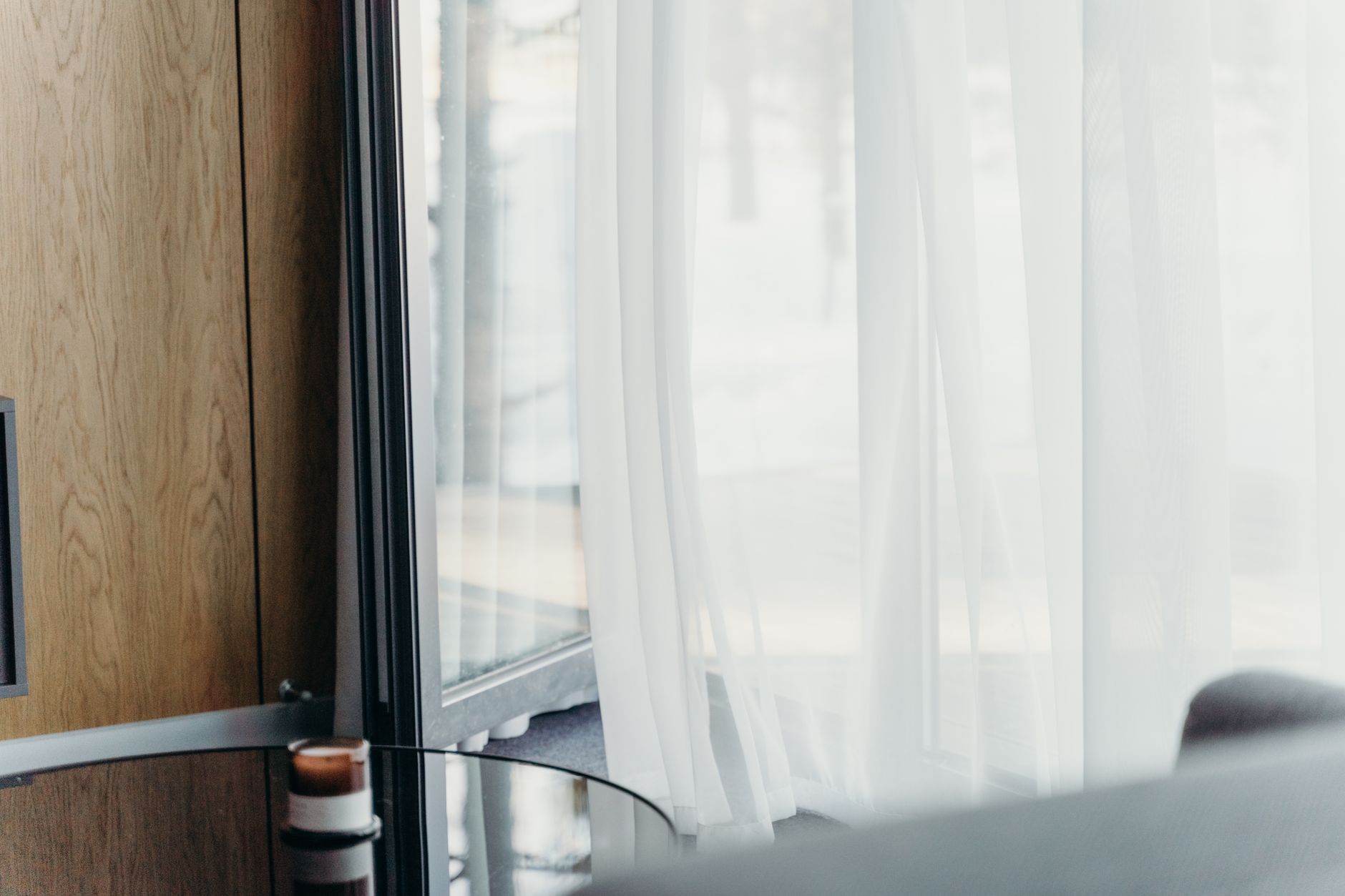 A hotel room with large bay windows and natural light filtered through shades