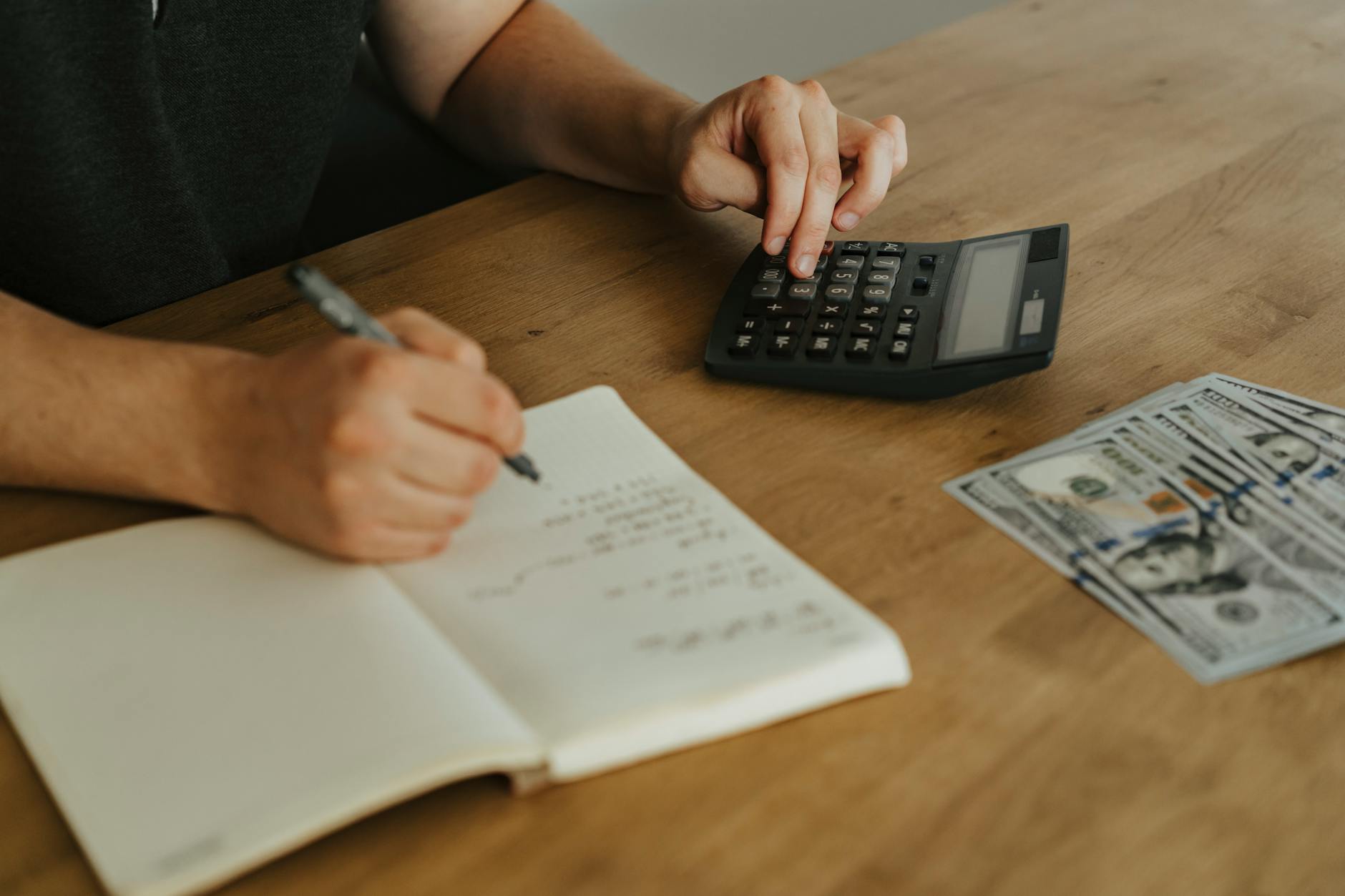 Open notebook with financial notes and a pen on a wooden desk