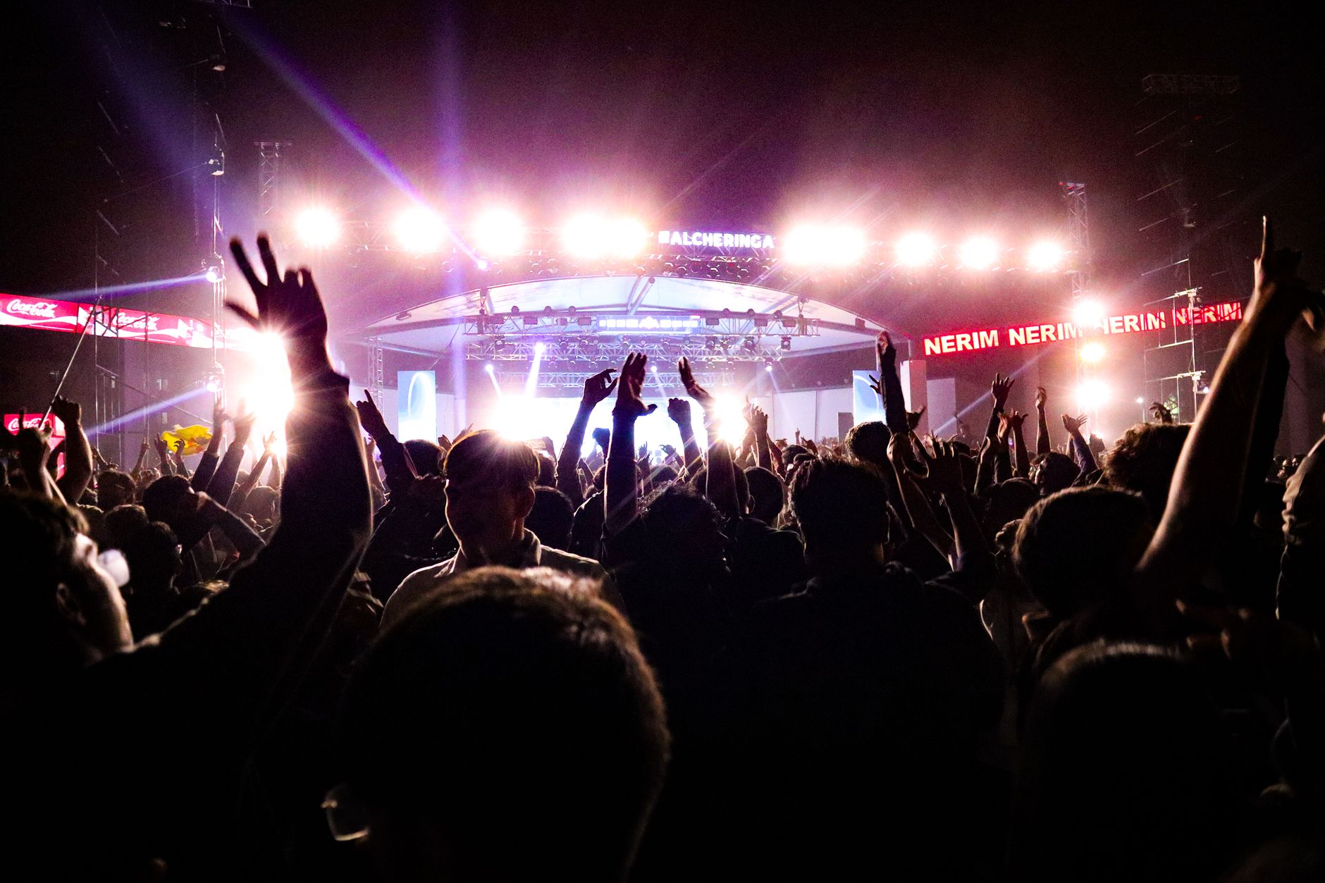 Festival-goers gathered near a lit concert stage at dusk