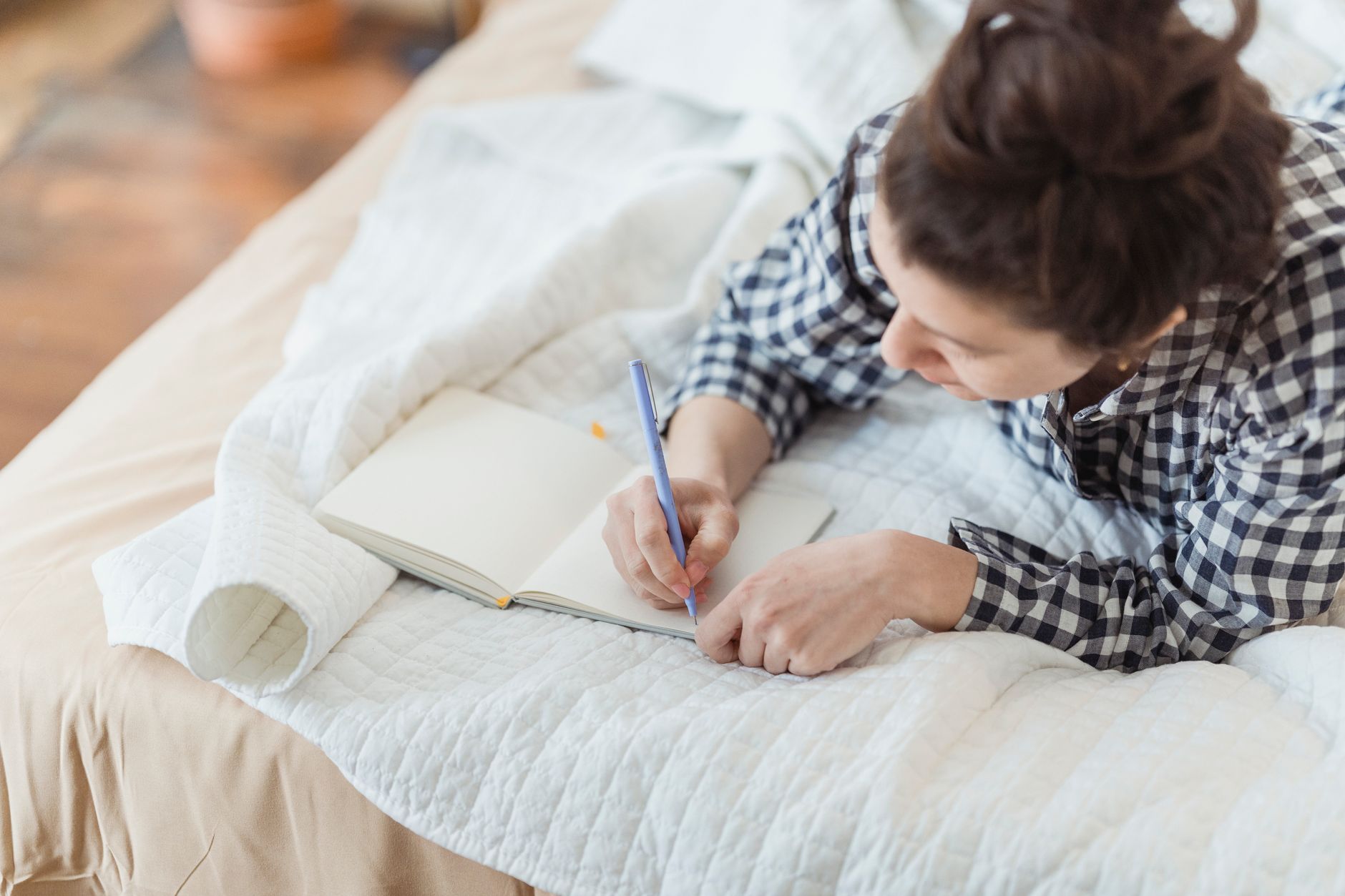 Woman sitting by a window writing in a journal during golden hour