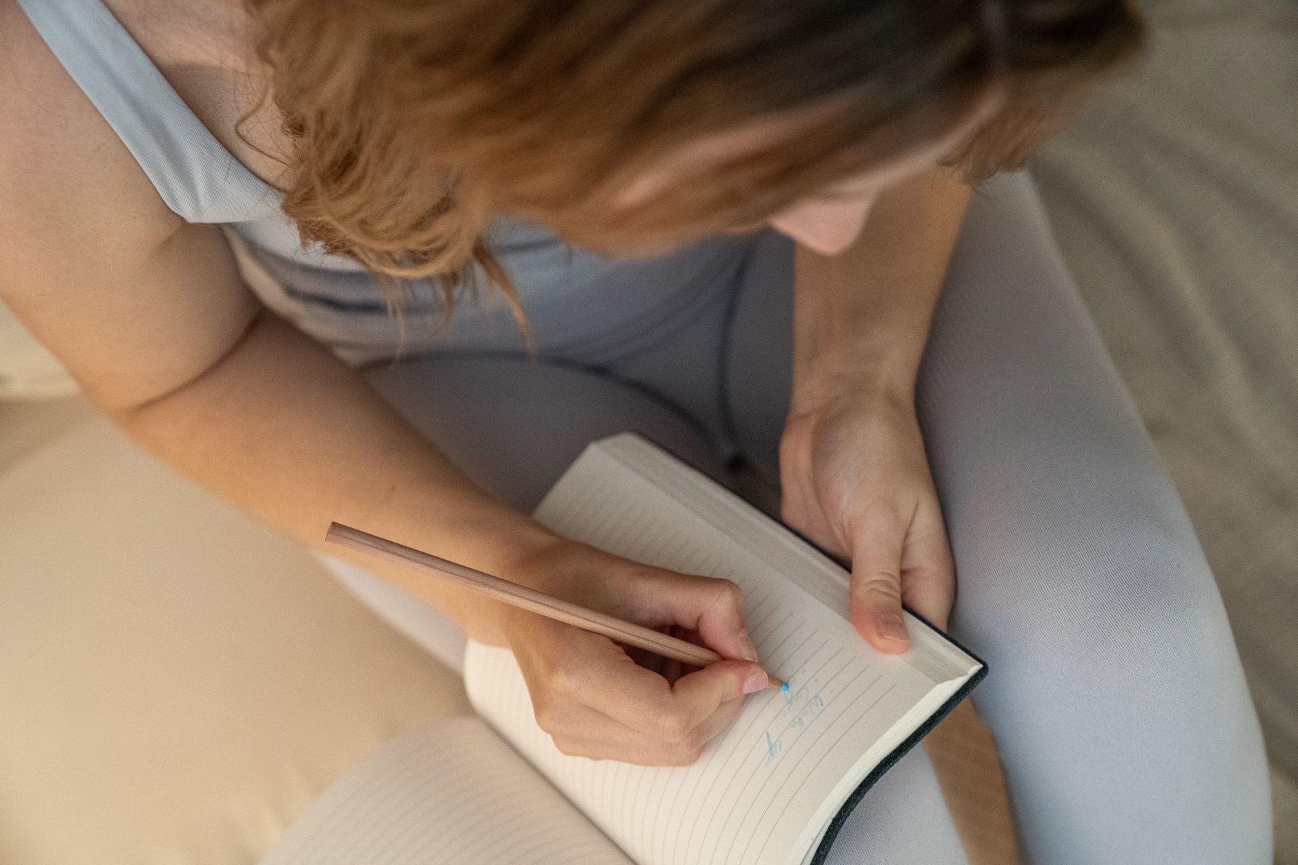 A woman writing in a journal at a quiet desk, representing emotional reflection during Mercury retrograde