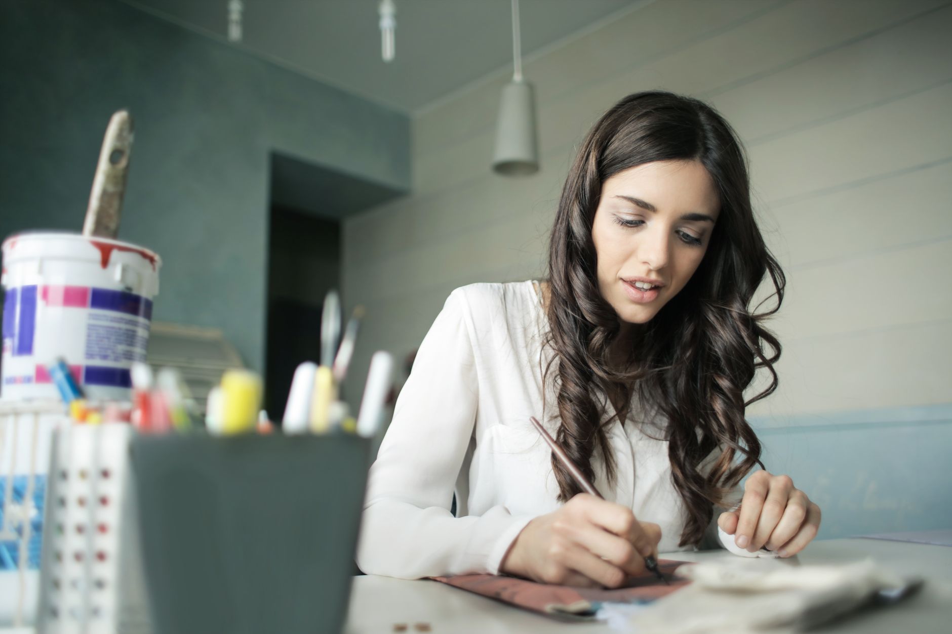 Woman working at a creative desk surrounded by reference materials and fabric samples