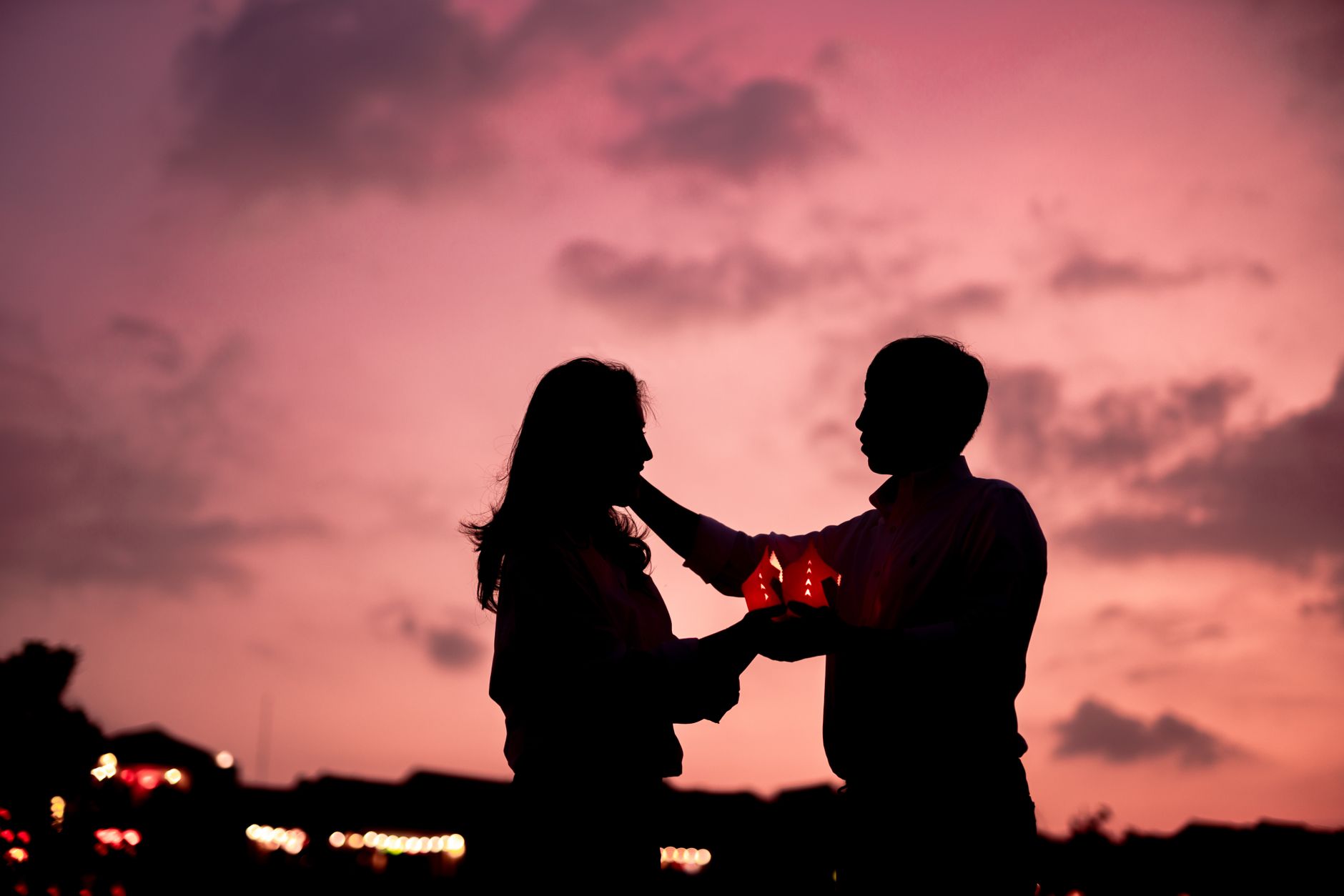 Two people standing close together against a warm sunset sky, suggesting romantic tension