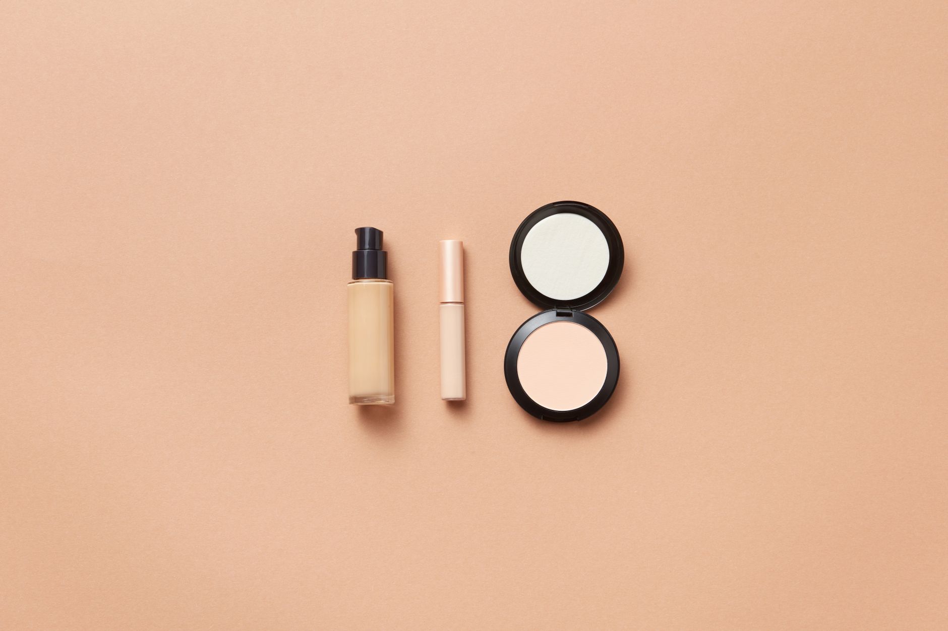 Beauty products arranged in a minimal flatlay including tinted skincare